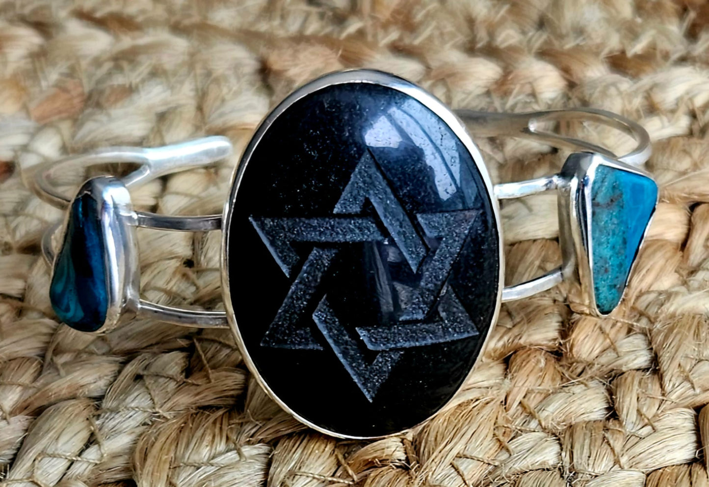 Sterling silver cuff bracelet with a 40x30mm black onyx cab, engraved with a star of David and 2 accent stones of Eilat stone from Israel, front view