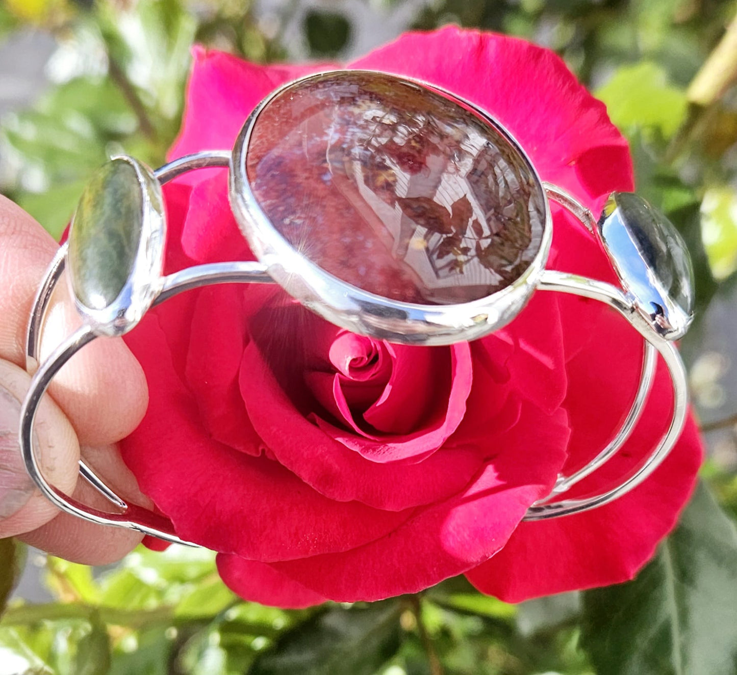 Sterling silver cuff bracelet with 40x30mm New Zealand jasper, from the Hotoritori stream and hand polished with a pair of New Zealand Pounamu (nephrite jade) cabs accenting. Jasper from the Hotoritori stream is known for beautiful red colour with flecks of many other colours mixed in, side view