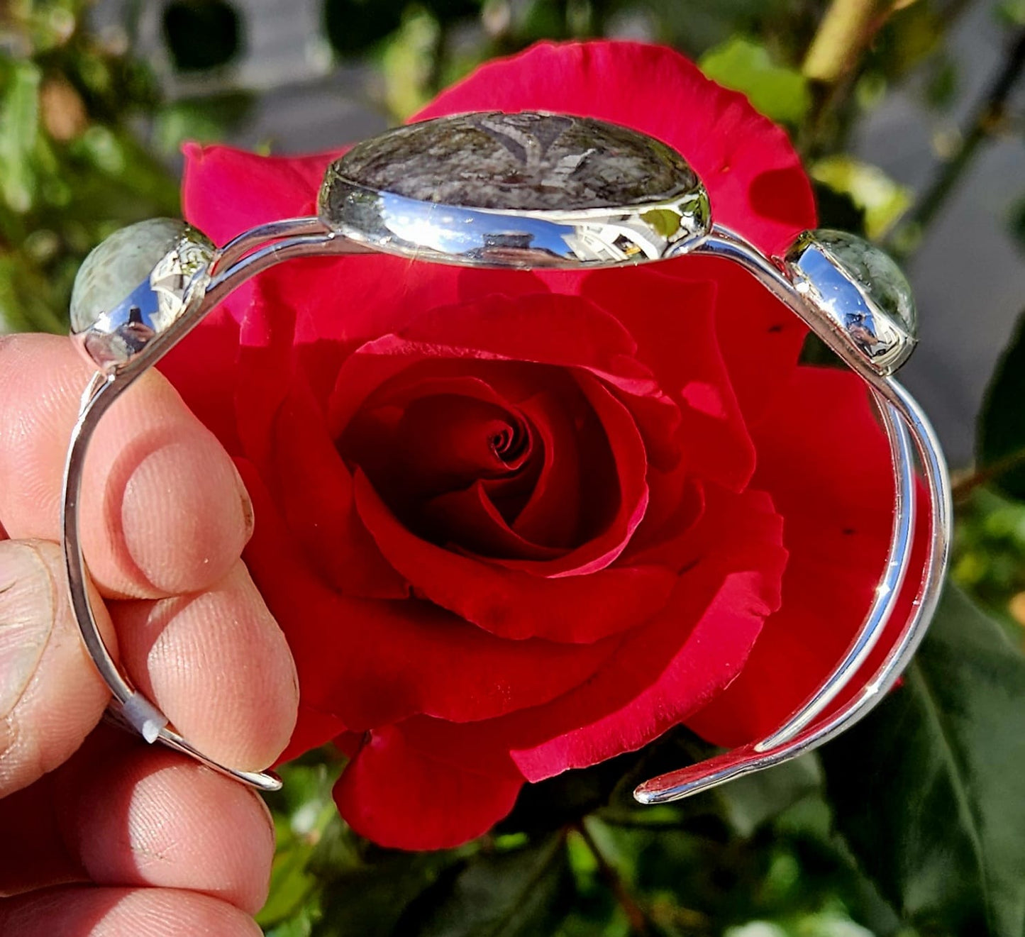 Sterling Silver Cuff bracelet with a 40x30mm cab of Taupo, New Zealand silver sheen obsidian, hand cut and engraved with a goddess symbol and flanked by 2 cabochons of New Zealand green grossular garnet, hand cut to 18x13mm cabs, side direct view.