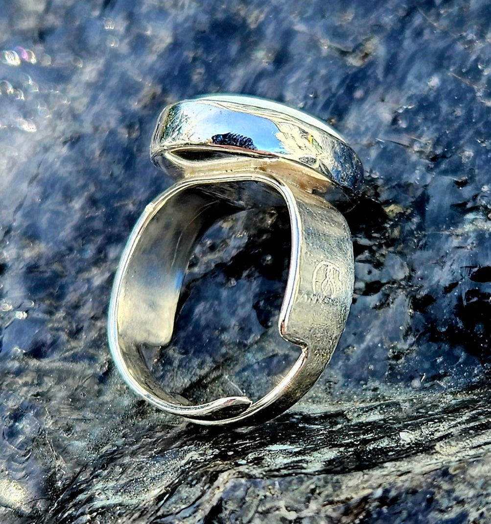 A beautiful 5.6ct Australian opal with lots of fire, hand cut and polished and set in a sterling silver, adjustable ring, side.