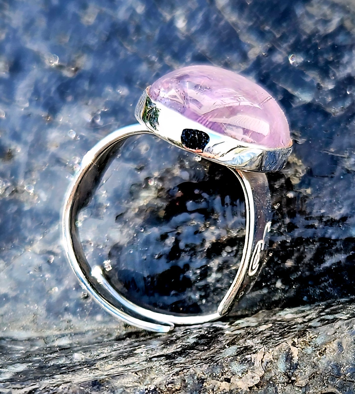 A soft purple amethyst, hand cut and polished to a 18x13mm cabochon and set in a sterling silver, adjustable ring, side.