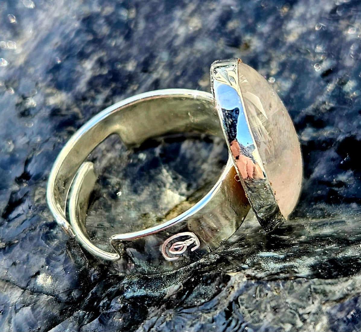 A sparkling clear quartz, hand cut and polished to a 18x13mm cabochon and set in a sterling silver, adjustable ring, side.