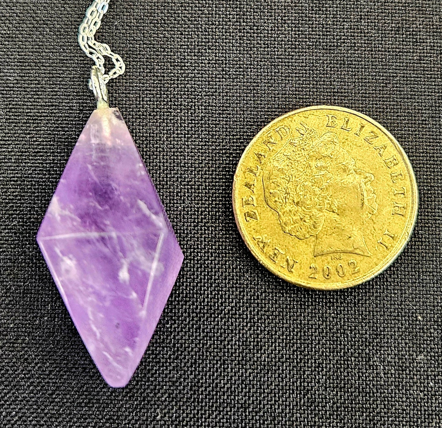 Amethyst Double Pyramid pendulum set to be worn as a necklace, so it's always handy, with a sterling silver chain with NZ one dollar coin for size comparison.