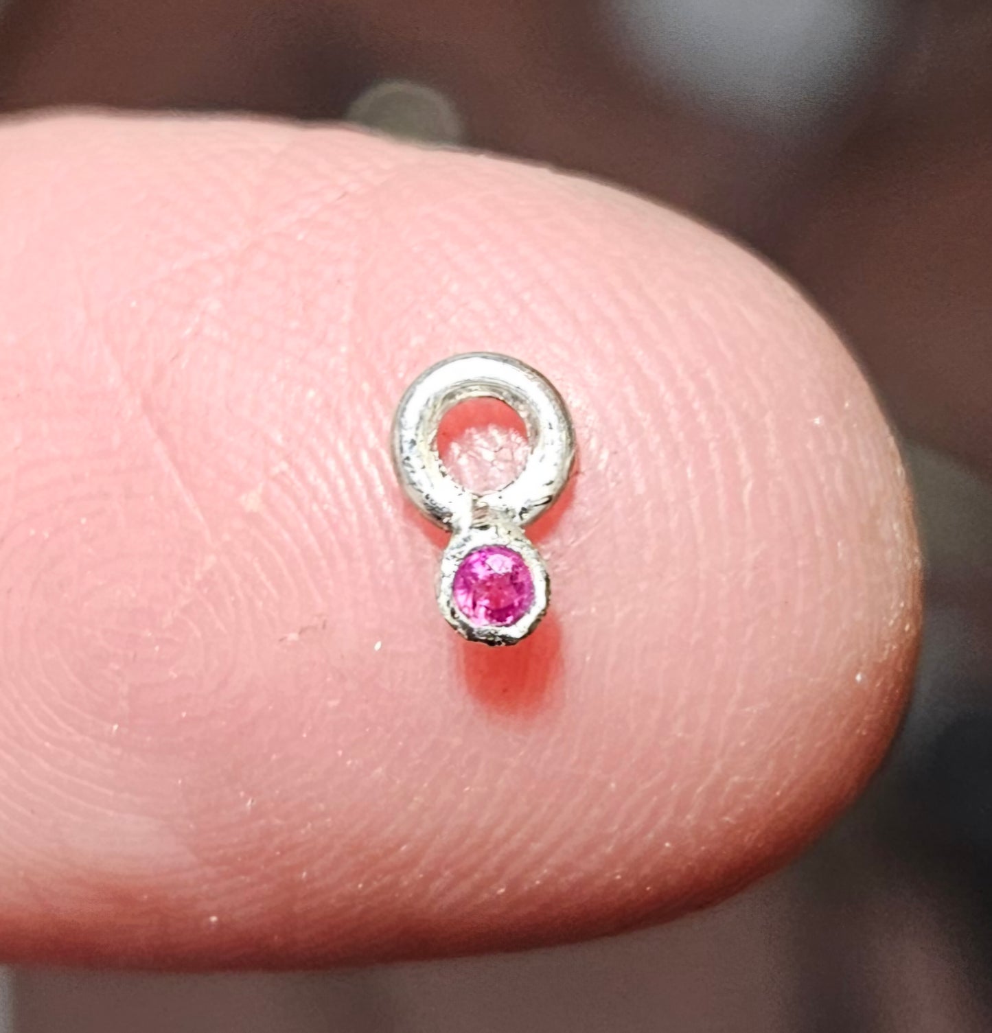 Small (40mm wide) Heart-Wing pendant with a ruby charm, all in solid sterling silver and a solid sterling silver heart chain, ruby charm alone on finger.