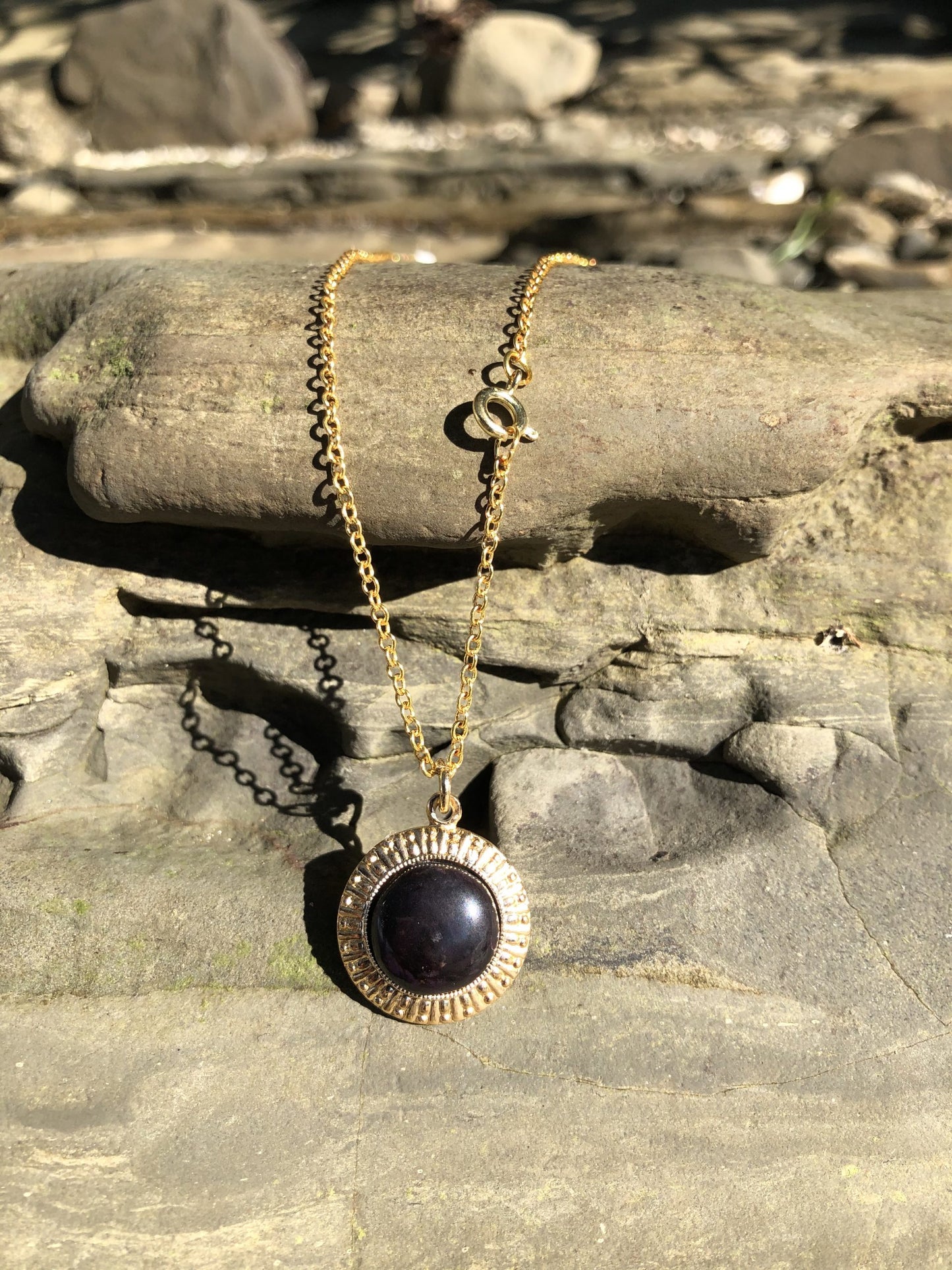 Necklace with black onyx, brilliant pure black, hand polished into a 14mm round cabochon and set in a gold plated setting with 19 inch chain on rocks