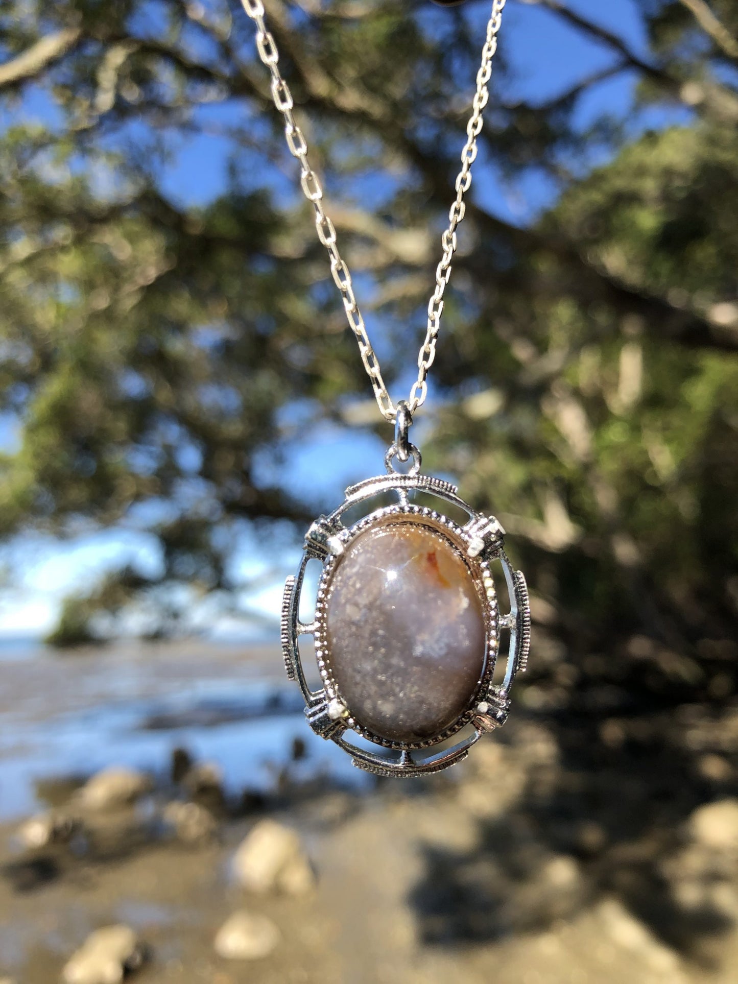 Necklace with a beautiful chert from Coromandel New Zealand with swirls of greys, browns and white. This stone is hand polished in a 20x15mm cabochon and set in a silver plated setting with a 19 inch chain on beach, lighter