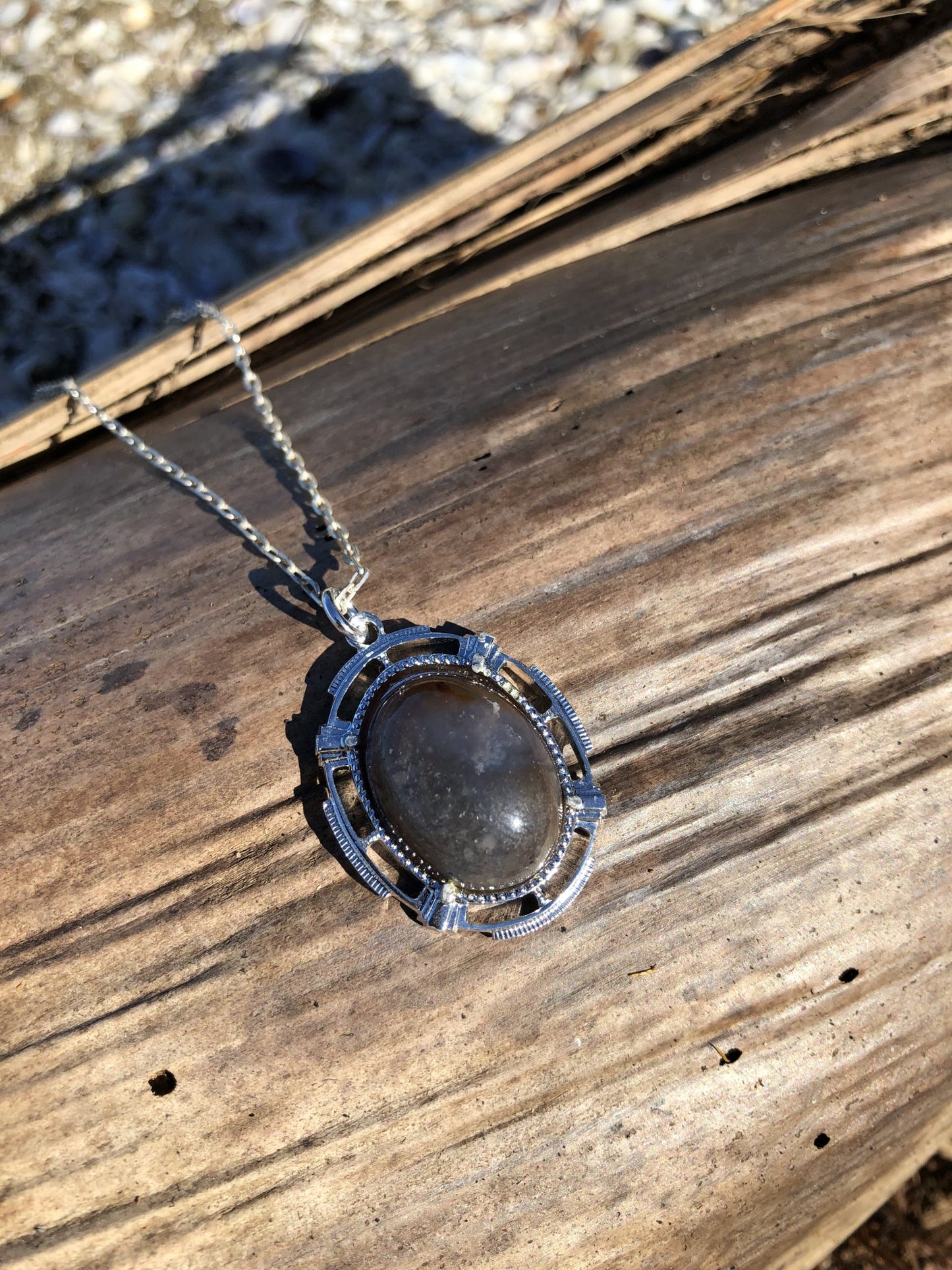 Necklace with a beautiful chert from Coromandel New Zealand with swirls of greys, browns and white. This stone is hand polished in a 20x15mm cabochon and set in a silver plated setting with a 19 inch chain on driftwood