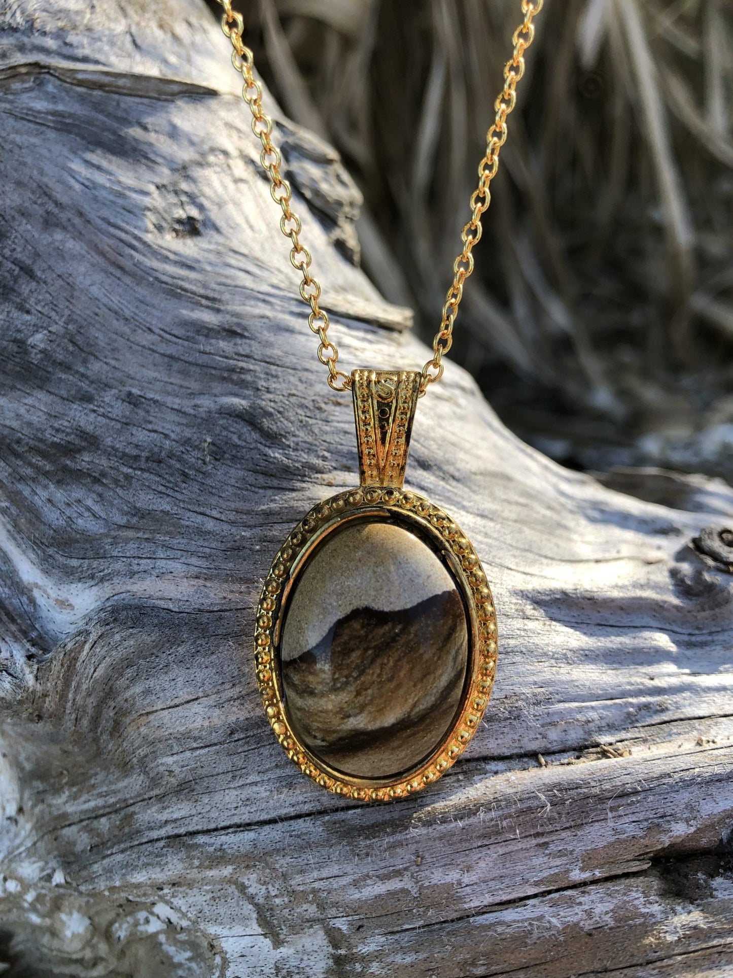Necklace with Picture Jasper from Oregon, USA with a beautiful mountain scene composed of browns, tans and greys. The stone is hand polished to a 25x18mm cabochon and set in a gold-plated setting with 19 inch chain, front