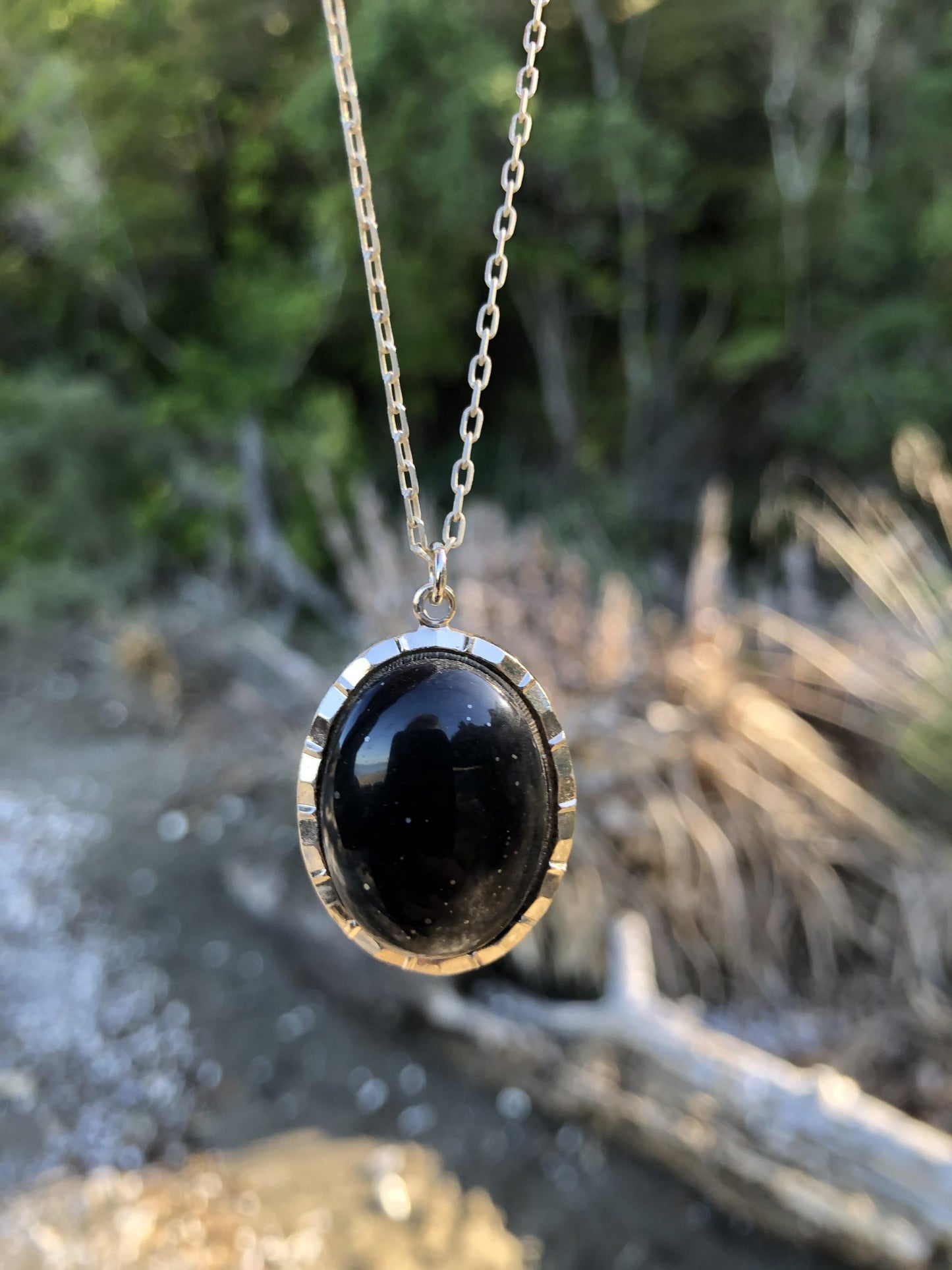 Necklace with a beautiful black chert from Coromandel New Zealand with sparkles of pyrites. This stone is hand polished in a 25x18mm cabochon and set in a silver-plated setting with a 19 inch chain.