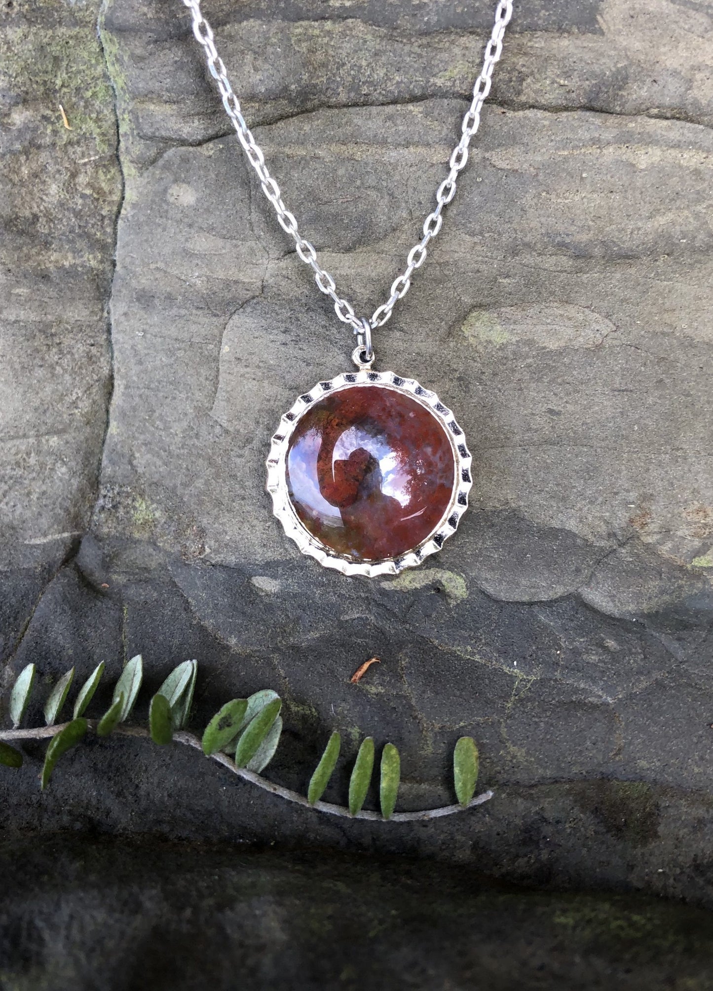 Necklace with New Zealand red Jasper with clear/gray agate, hand polished to a 16mm round cabochon and set in a silver-plated setting with 19 inch chain.