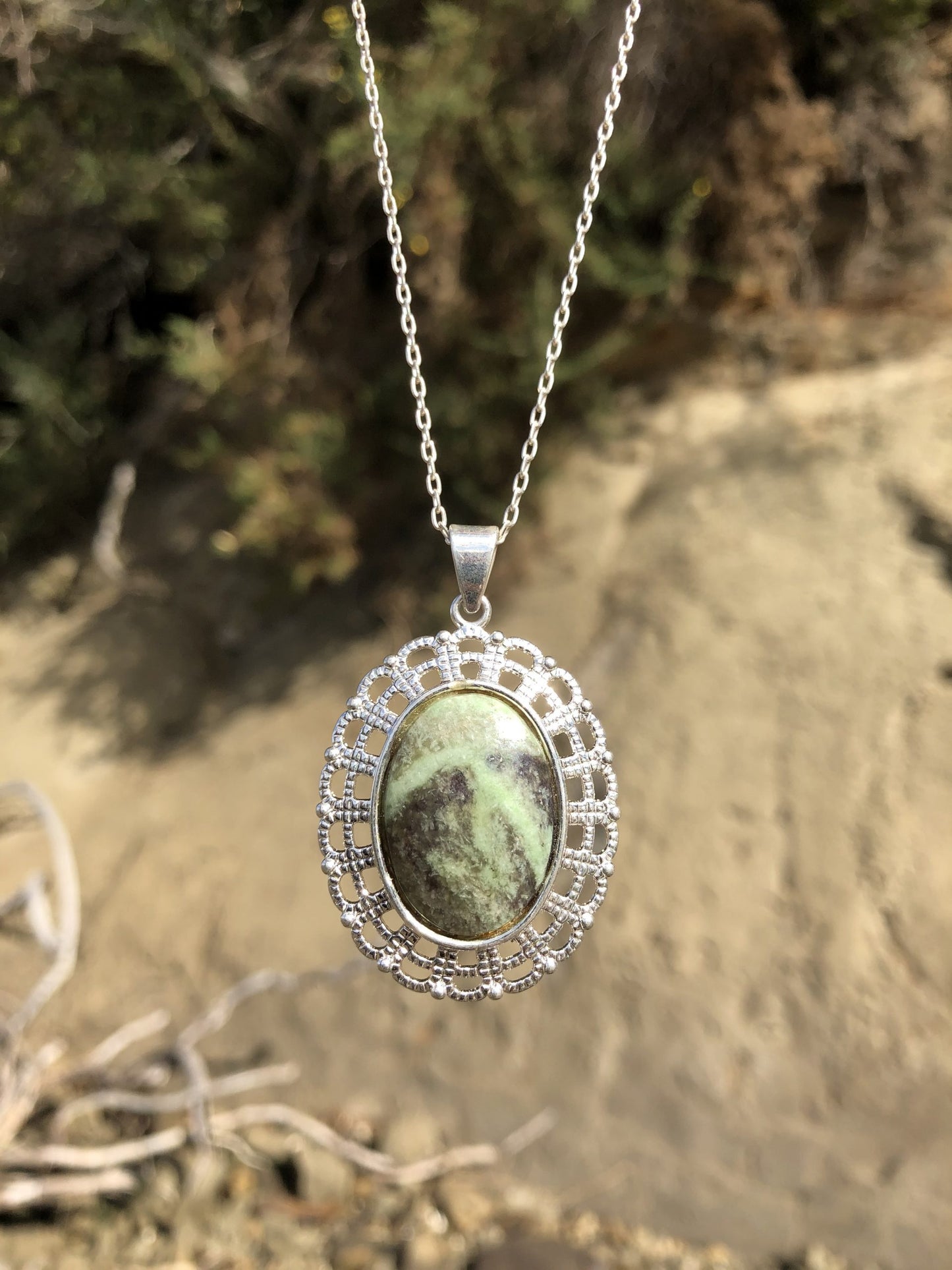 Necklace with a New Zealand Pounamu (Greenstone, NZ Nephrite) hand polished to a 25x18mm cabochon and set in a silver-plated setting with a 19 inch chain, darker