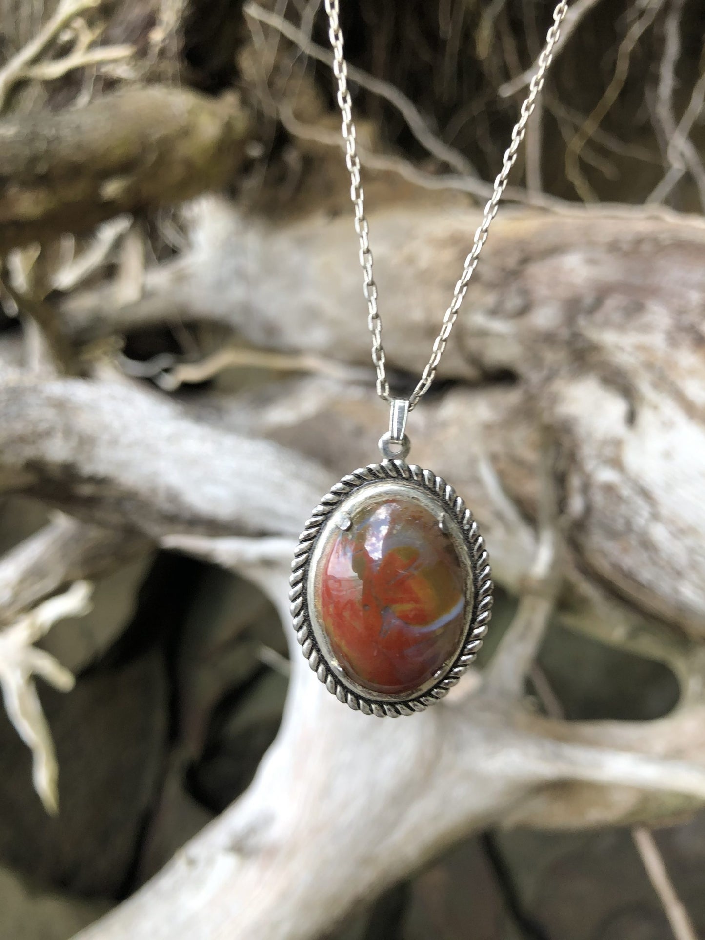 Necklace with New Zealand Chakra Jasper, hand polished to a 25x18mm cabochon and set in a silver plated setting with 19 inch chain. Chakra jasper is a special form of jasper found in New Zealand that contains all (or most) of the chakra stone within it. This stone is predominantly red with orange, yellow, green, blue, brown, black and white, close