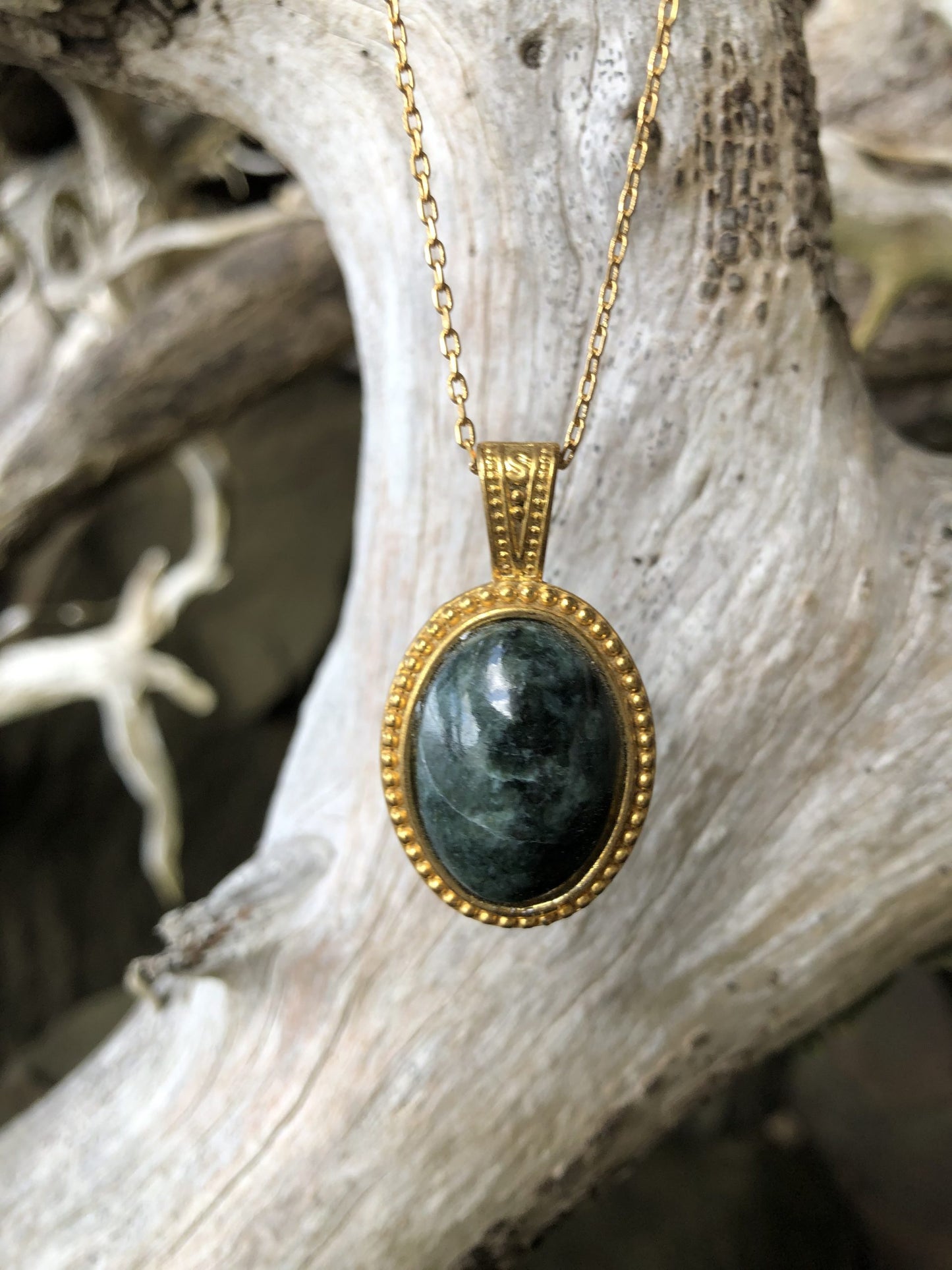 Necklace with natural New Zealand serpentine, dark green with subtle markings, hand polished to a 25x18mm cabochon and set in a gold-plated setting with 19 inch chain on branch