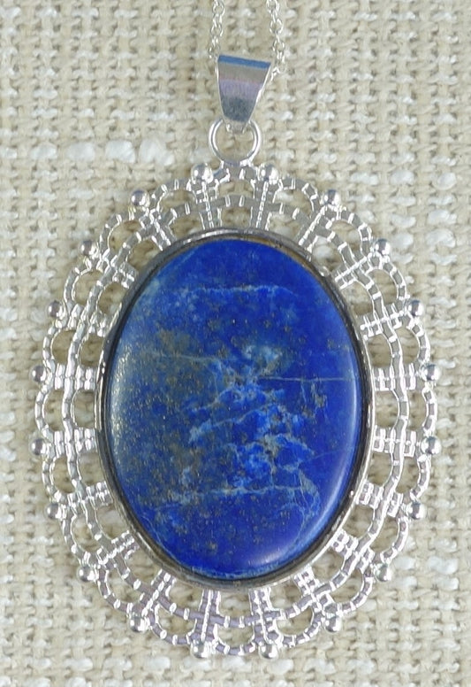 Necklace with large 40x30mm cabochon of natural Lapis Lazuli from Afghanistan with deep Lapis blue and some fine lines of white quarts and speckles of golden pyrites, hand polished and set in a silver plated setting with 19 inch chain.