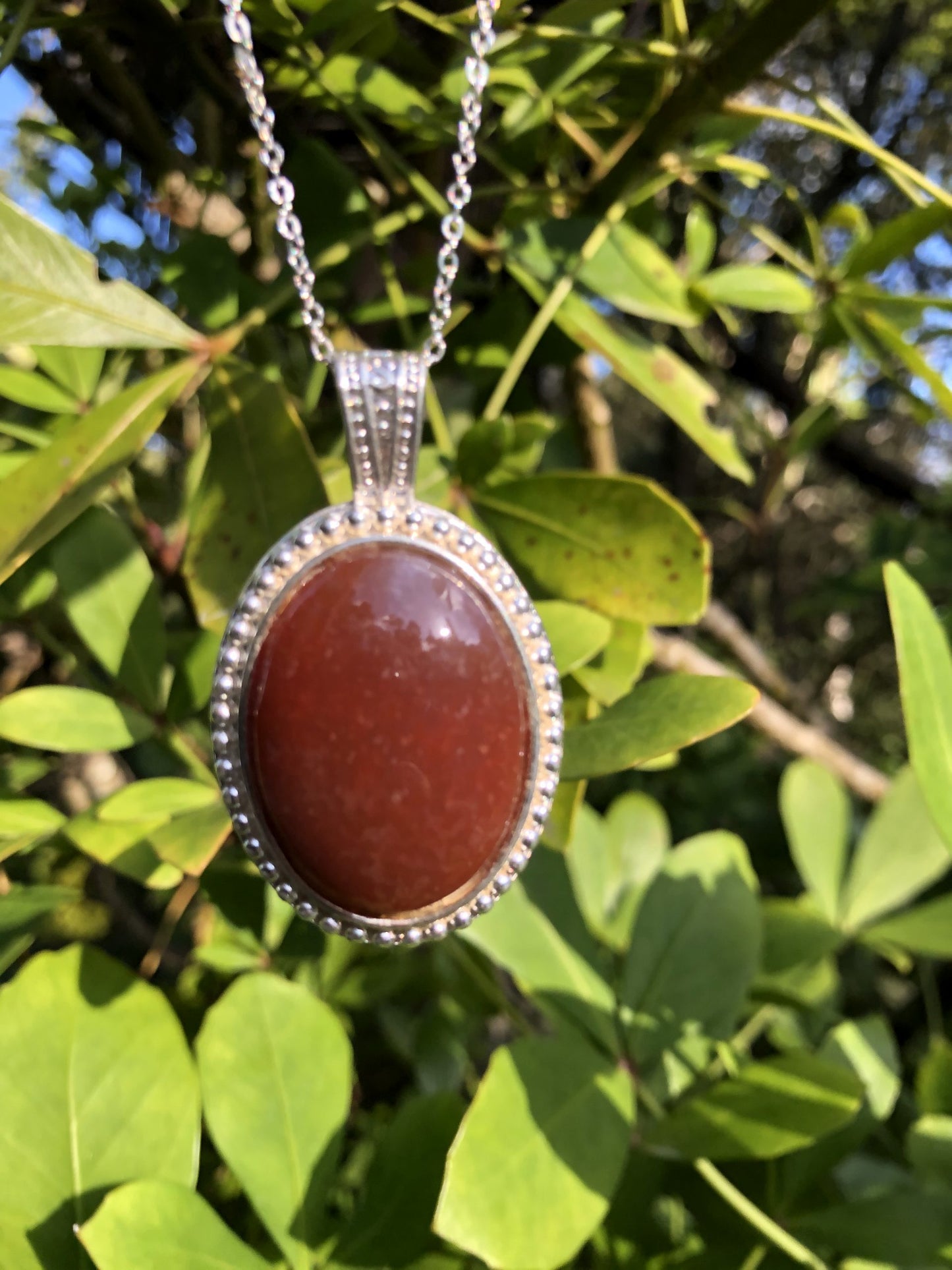 Necklace with New Zealand red Jasper, rich, deep red with tiny flecks of colour variation, hand polished to a 30x22mm cabochon and set in a silver-plated setting with 19 inch chain.