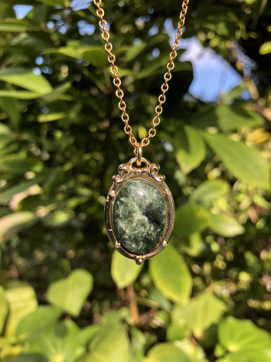 Necklace with a New Zealand Pounamu (Greenstone, NZ Nephrite) hand polished to a 20x15mm cabochon and set in a gold plated setting with a 19 inch chain.