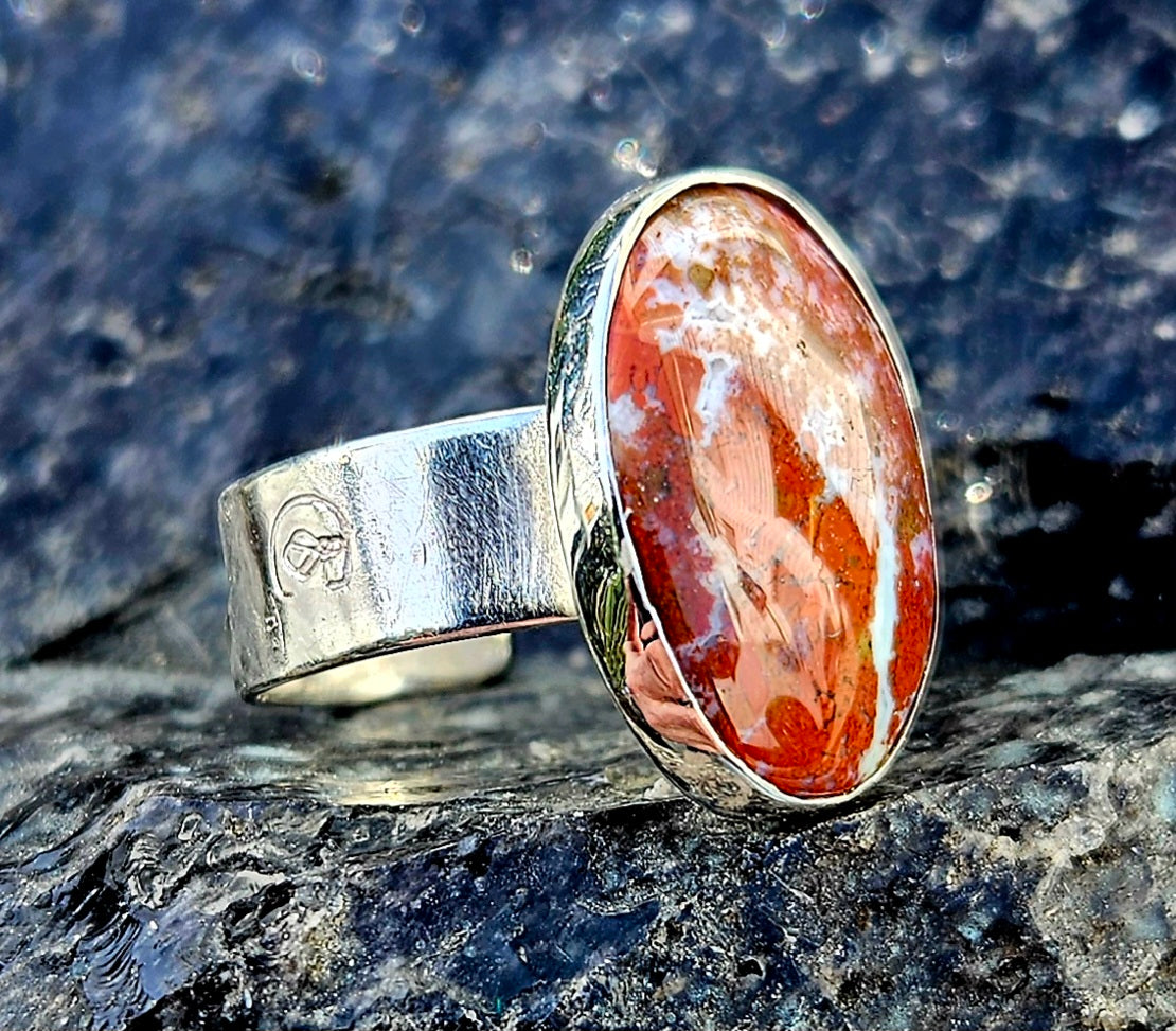 A vibrant red New Zealand jasper with striking lines of white quartz running through it, hand cut and polished to an 18x13mm cabochon and set in a sterling silver, adjustable ring, angle.