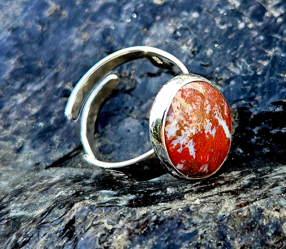 A vibrant red New Zealand jasper with striking lines of white quartz running through it, hand cut and polished to an 18x13mm cabochon and set in a sterling silver, adjustable ring, side.