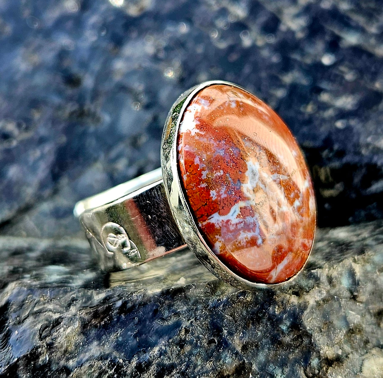 A vibrant red New Zealand jasper with striking lines of white quartz running through it, hand cut and polished to an 18x13mm cabochon and set in a sterling silver, adjustable ring, angle.