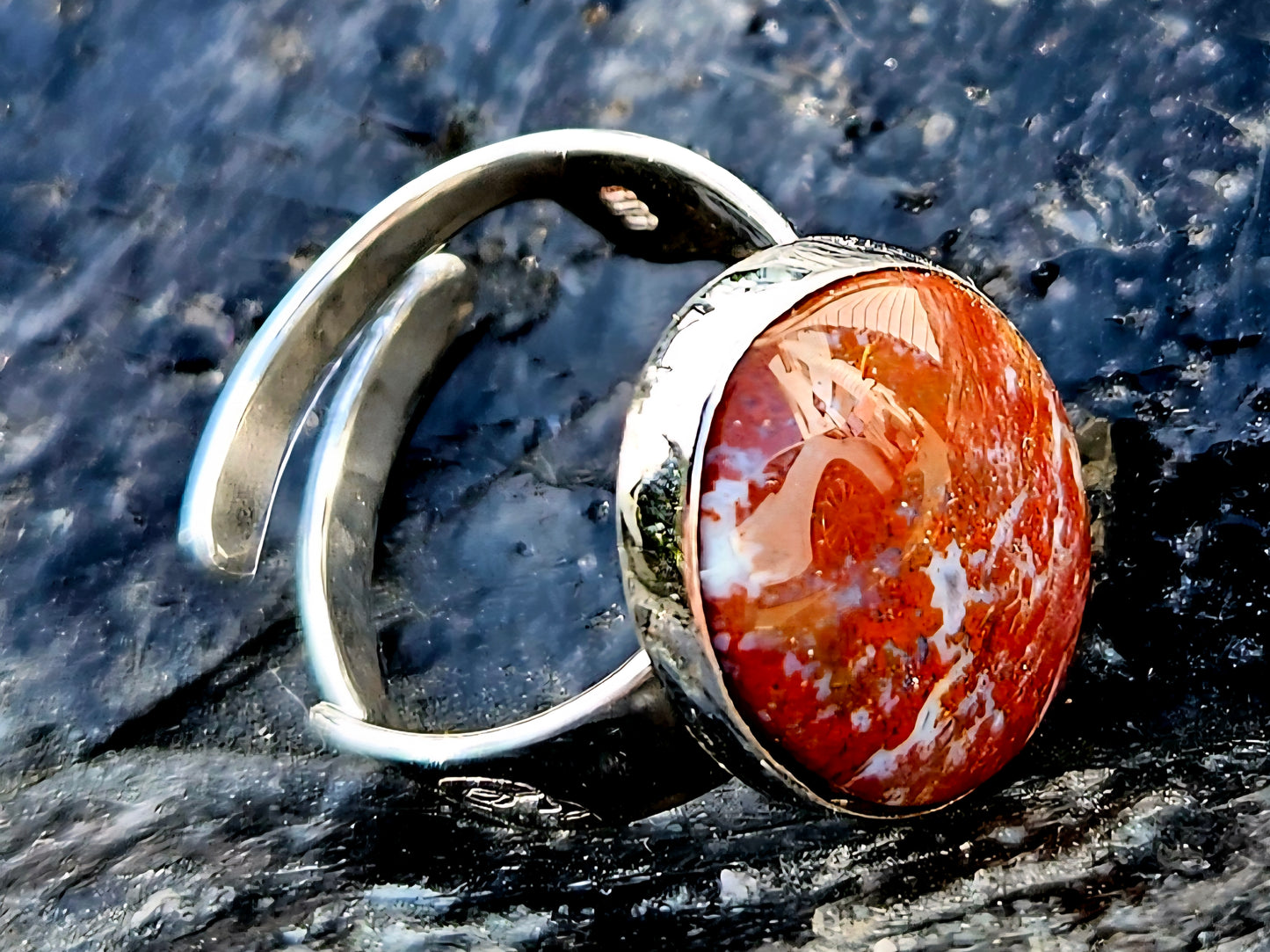A vibrant red New Zealand jasper with striking lines of white quartz running through it, hand cut and polished to an 18x13mm cabochon and set in a sterling silver, adjustable ring, side.
