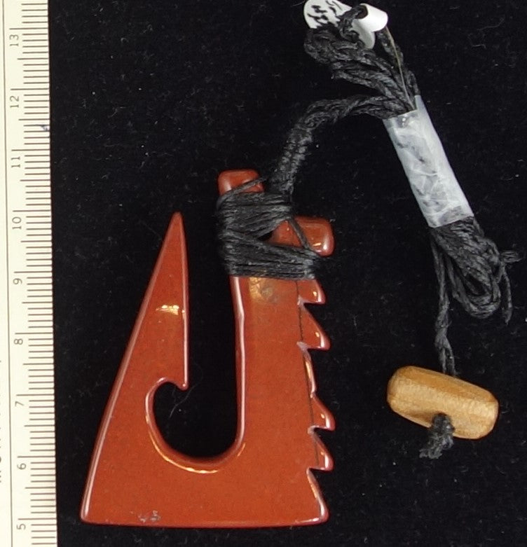 Hand carved New Zealand red jasper carved into a modern take on a traditional fish hook, bound and hung with a hand braided string and swamp-kauri wood toggle.