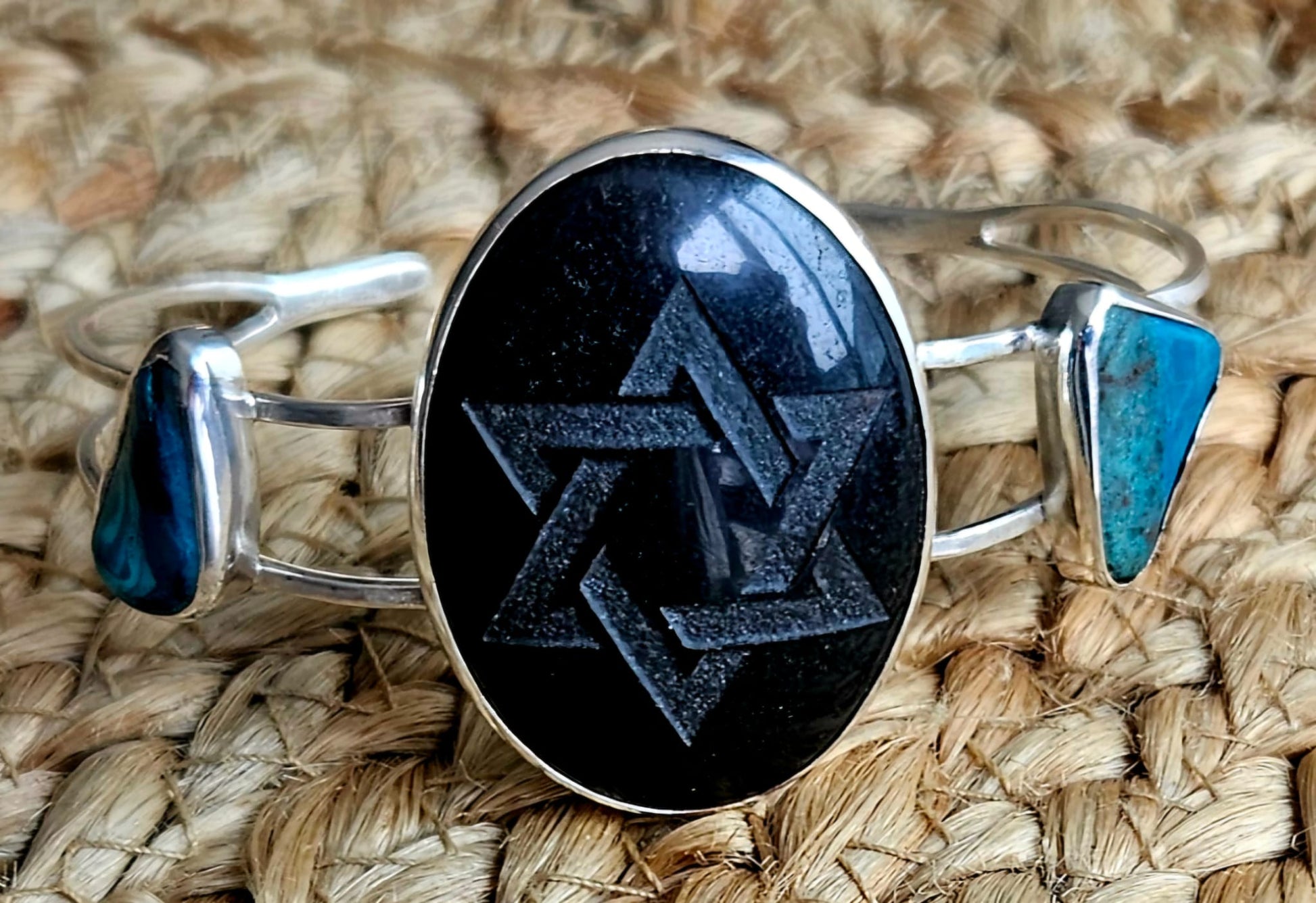 Sterling silver cuff bracelet with a 40x30mm black onyx cab, engraved with a star of David and 2 accent stones of Eilat stone from Israel, front view