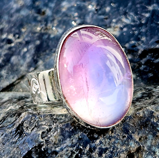 A soft purple amethyst, hand cut and polished to a 18x13mm cabochon and set in a sterling silver, adjustable ring, top.