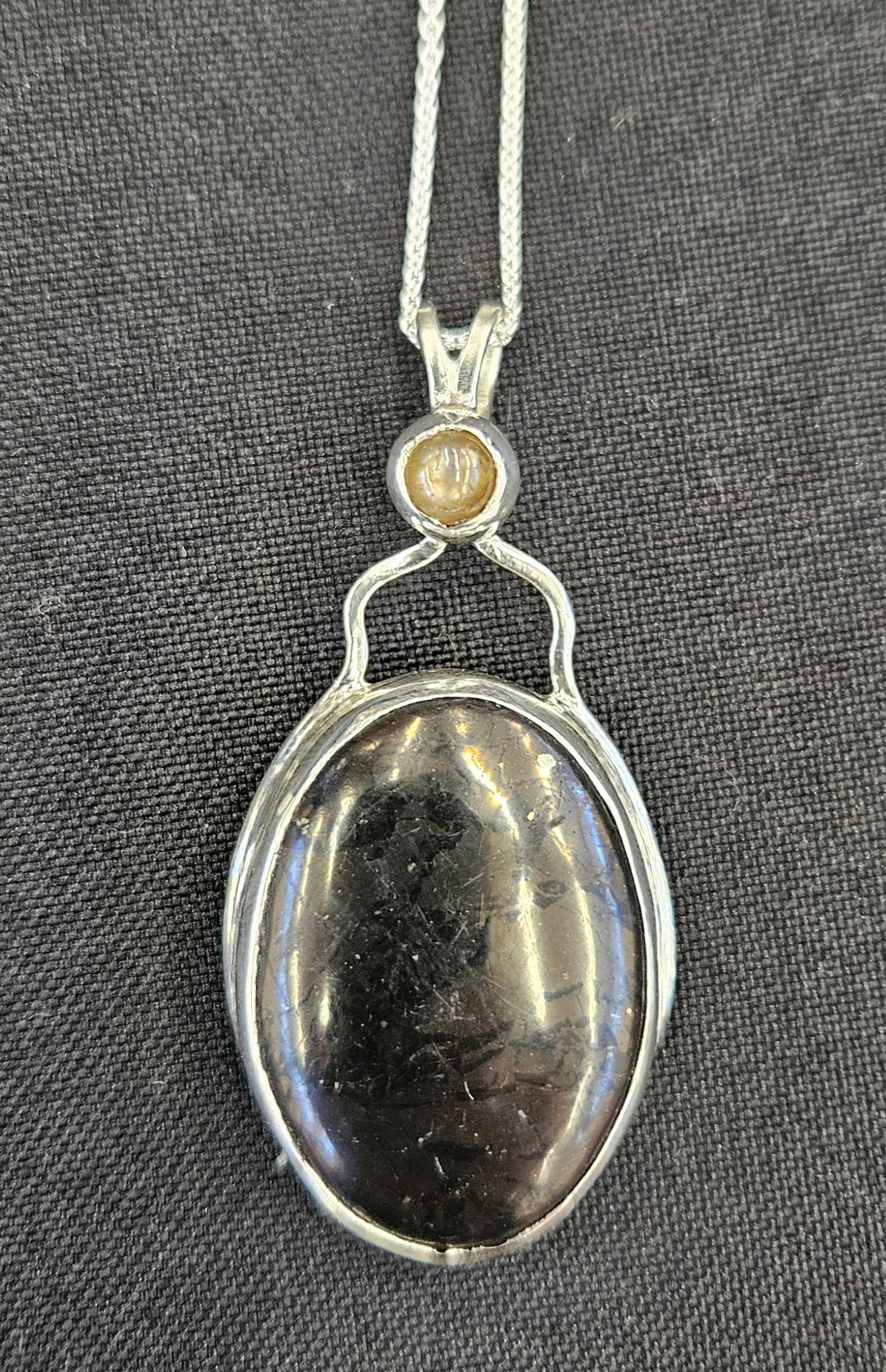 Shungite pendant with Moonstone accent in sterling silver and 18 inch sterling silver chain.