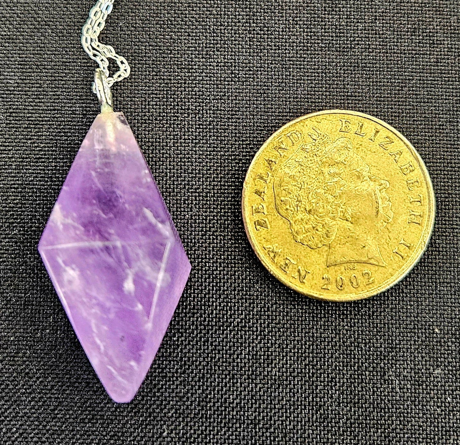 Amethyst Double Pyramid pendulum set to be worn as a necklace, so it's always handy, with a sterling silver chain with NZ one dollar coin for size comparison.