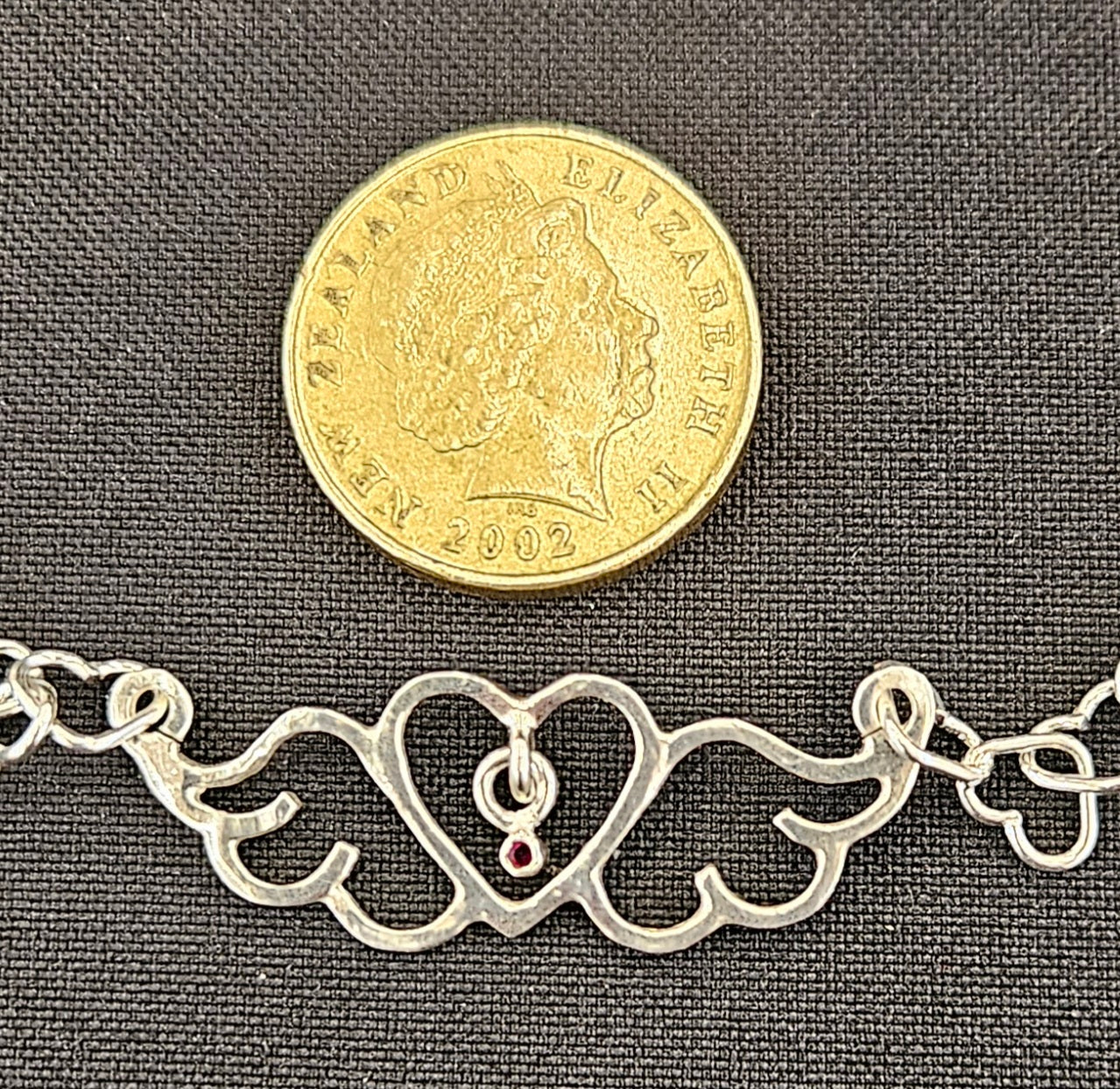 Small (40mm wide) Heart-Wing pendant with a ruby charm, all in solid sterling silver and a solid sterling silver heart chain with NZ one dollar coin for size comparison.