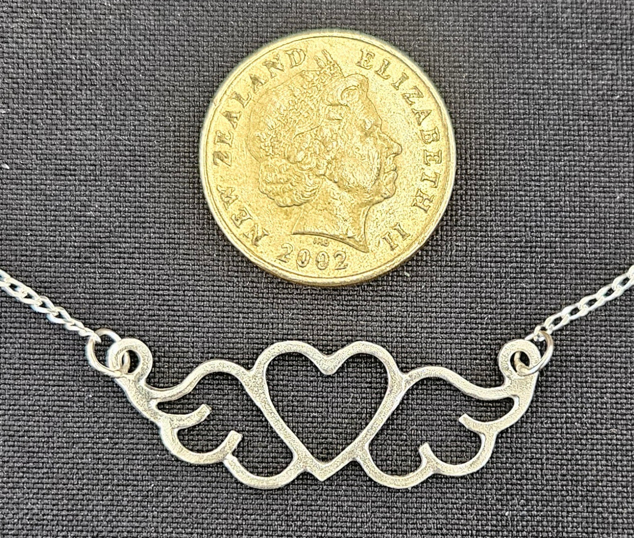 Small (40mm wide) Heart-Wing pendant in solid sterling silver and a solid sterling silver fine chain with NZ one dollar coin for size comparison.