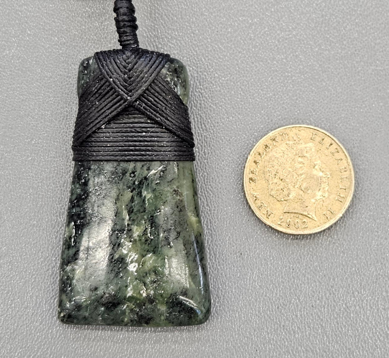 Kawakawa New Zealand Pounamu Toki, medium size, hand made with hand braided chord and NZ Pounamu toggle with NZ one dollar coin for size comparison.