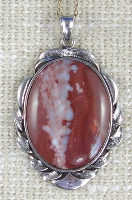Neclace with Jasper from the Fourth Branch of the Tairua River in Coromandel New Zealand with rich red jasper and a thick vein of blue chalcedony running up the middle. Hand cut into a 40x30mm cabochon and set in a silver plated setting with 19 inch chain on burlap