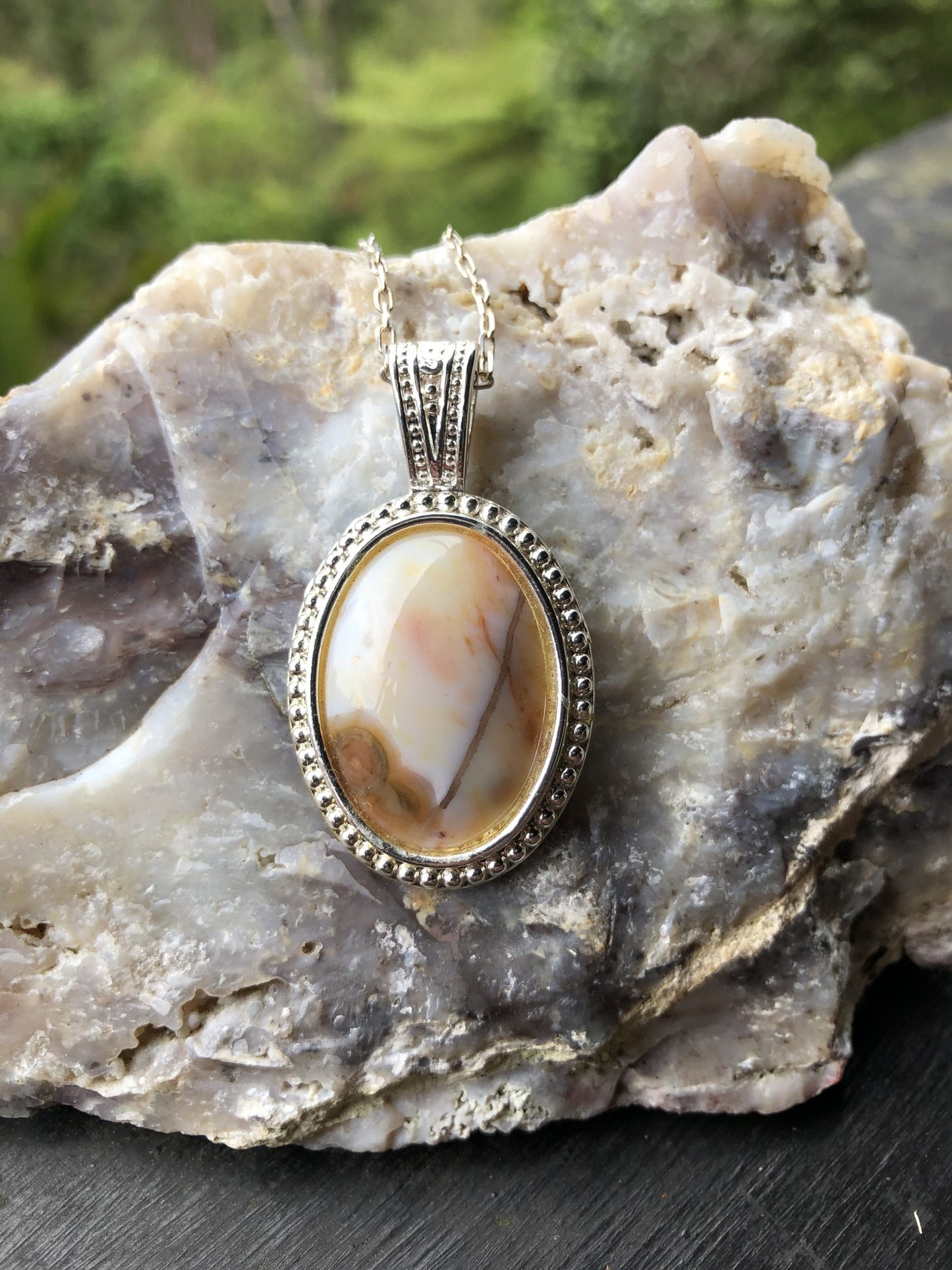Necklace with Ocean Jasper from Madegascar, white with red and brown patterns, hand polished to a 25x18mm cabochon and set in a silver plated setting with 19 inch chain, close-up on Cinebar