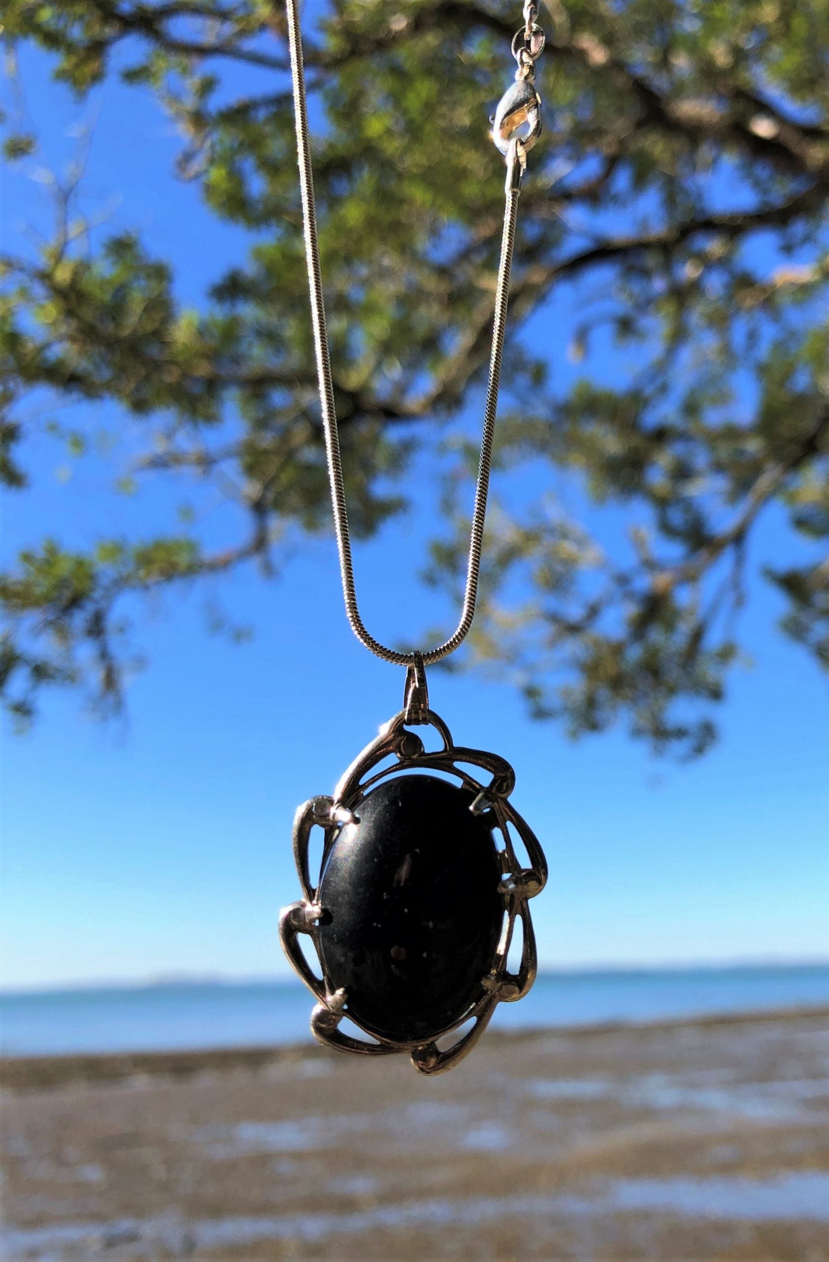 Necklace with New Zealand Kaeo obsidian, pure glistening black, hand polished to a 25x18mm oval cabochon and set in a sterling silver setting with 24 inch sterling silver chain on sky