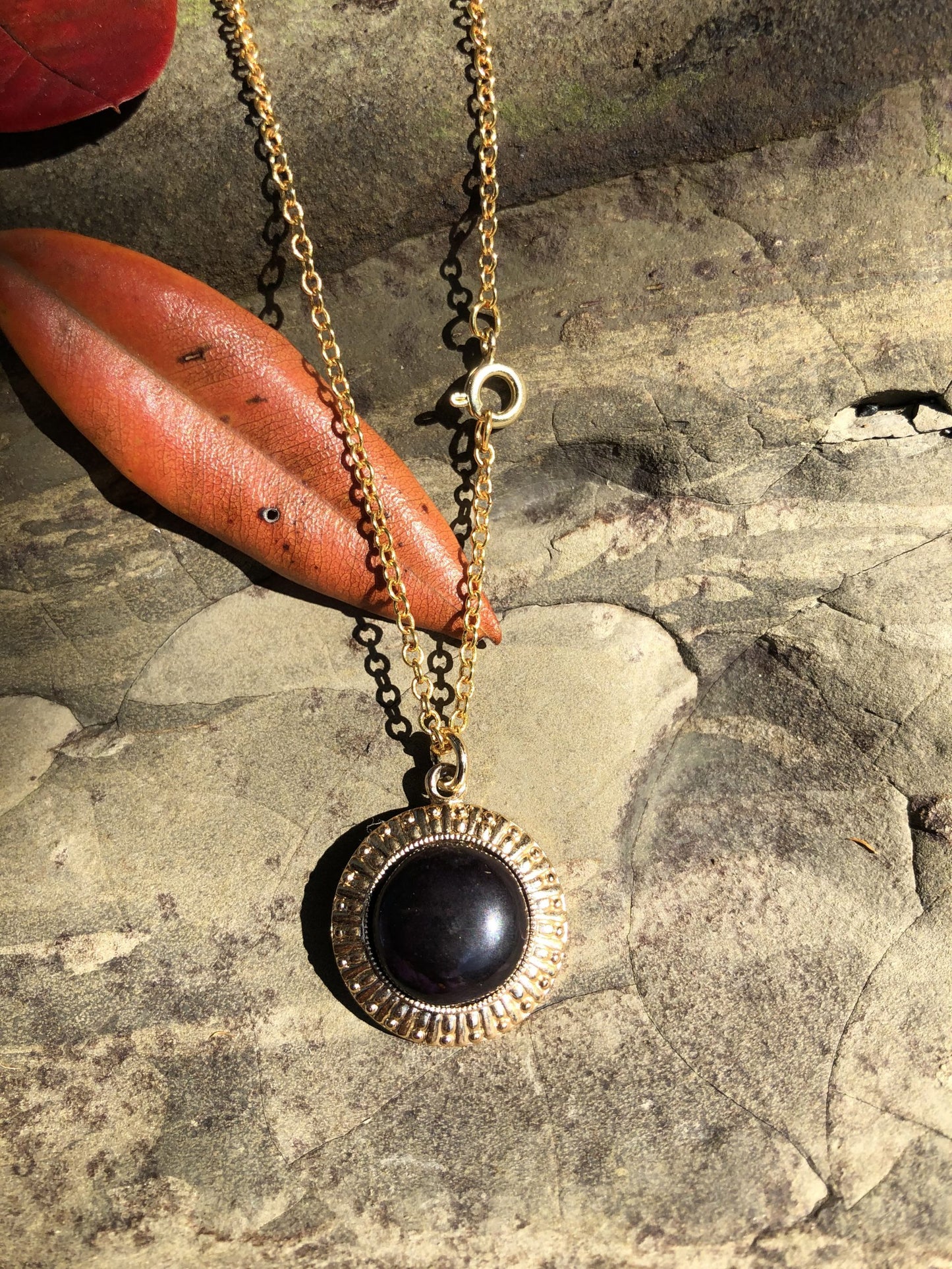 Necklace with black onyx, brilliant pure black, hand polished into a 14mm round cabochon and set in a gold plated setting with 19 inch chain, with leaves