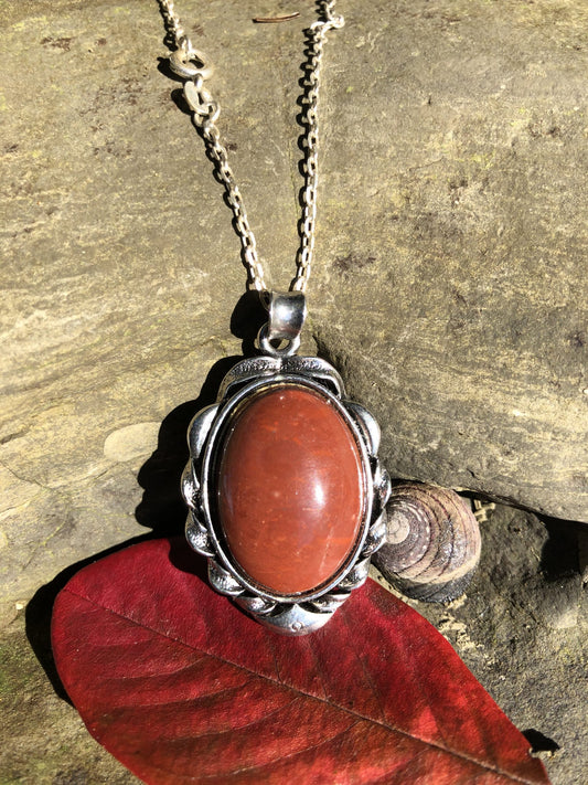 Necklace with New Zealand red Jasper, rich, deep red with tiny flecks of colour variation, hand polished to a 25x18mm cabochon and set in a silver plated setting with 19 inch chain, on beach