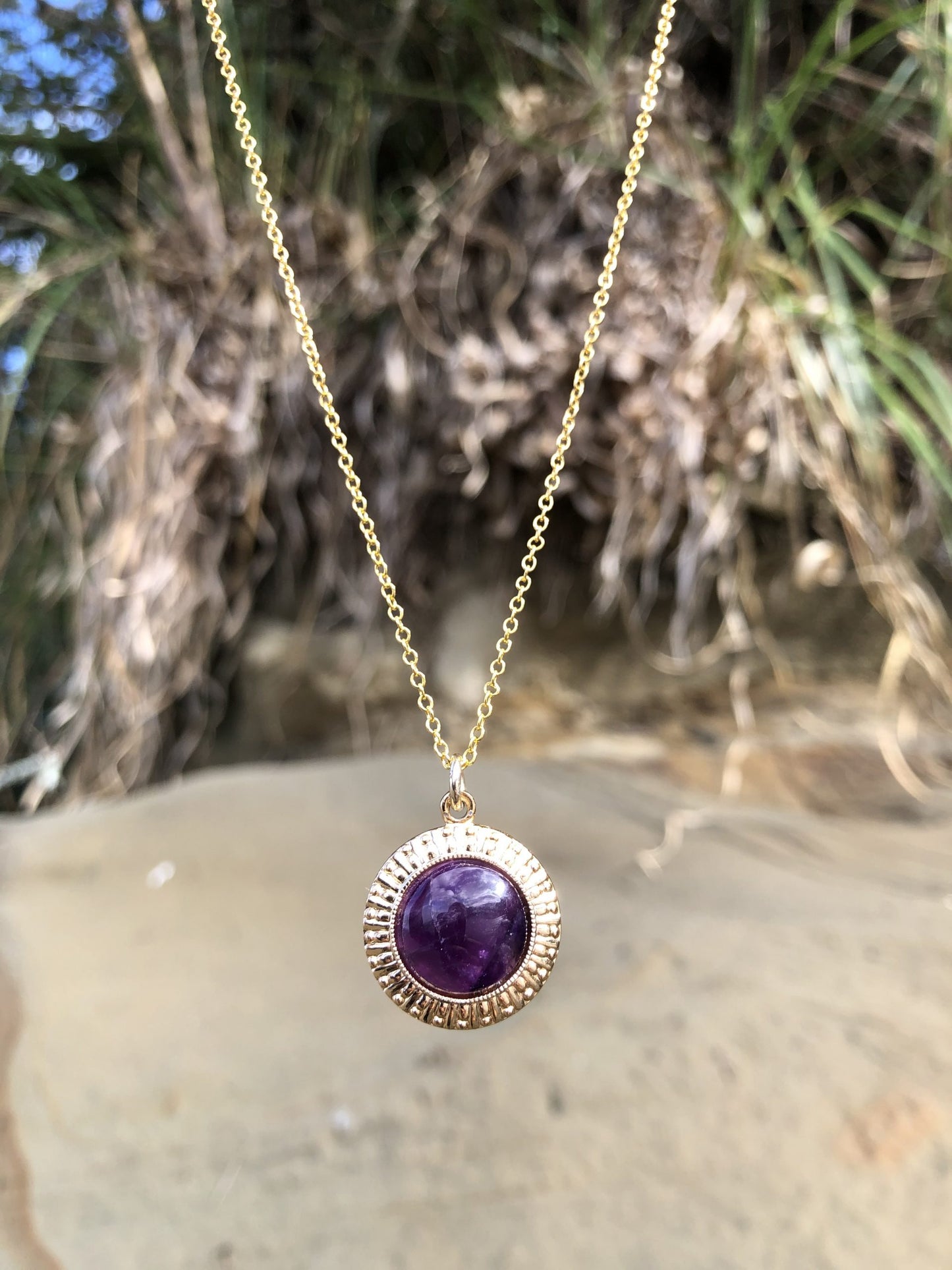 Necklace with rich, dark purple Amethyst, hand polished to a 14mm round cabochon and set in a gold plated setting with 19 inch chain.