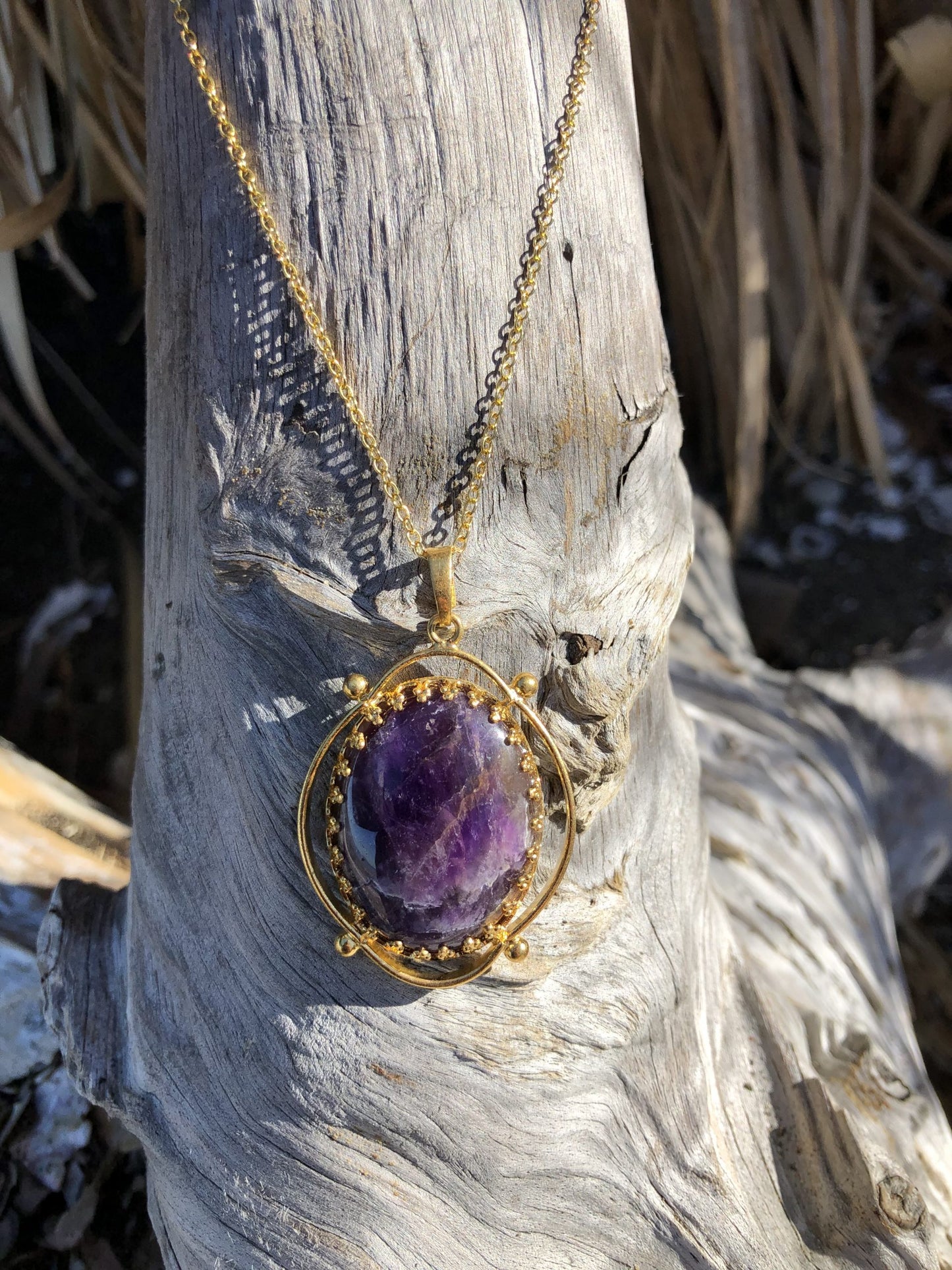Necklace with rich, dark purple Amethyst, hand polished to a 30x22mm oval cabochon and set in a gold plated setting with 19 inch chain on driftwood
