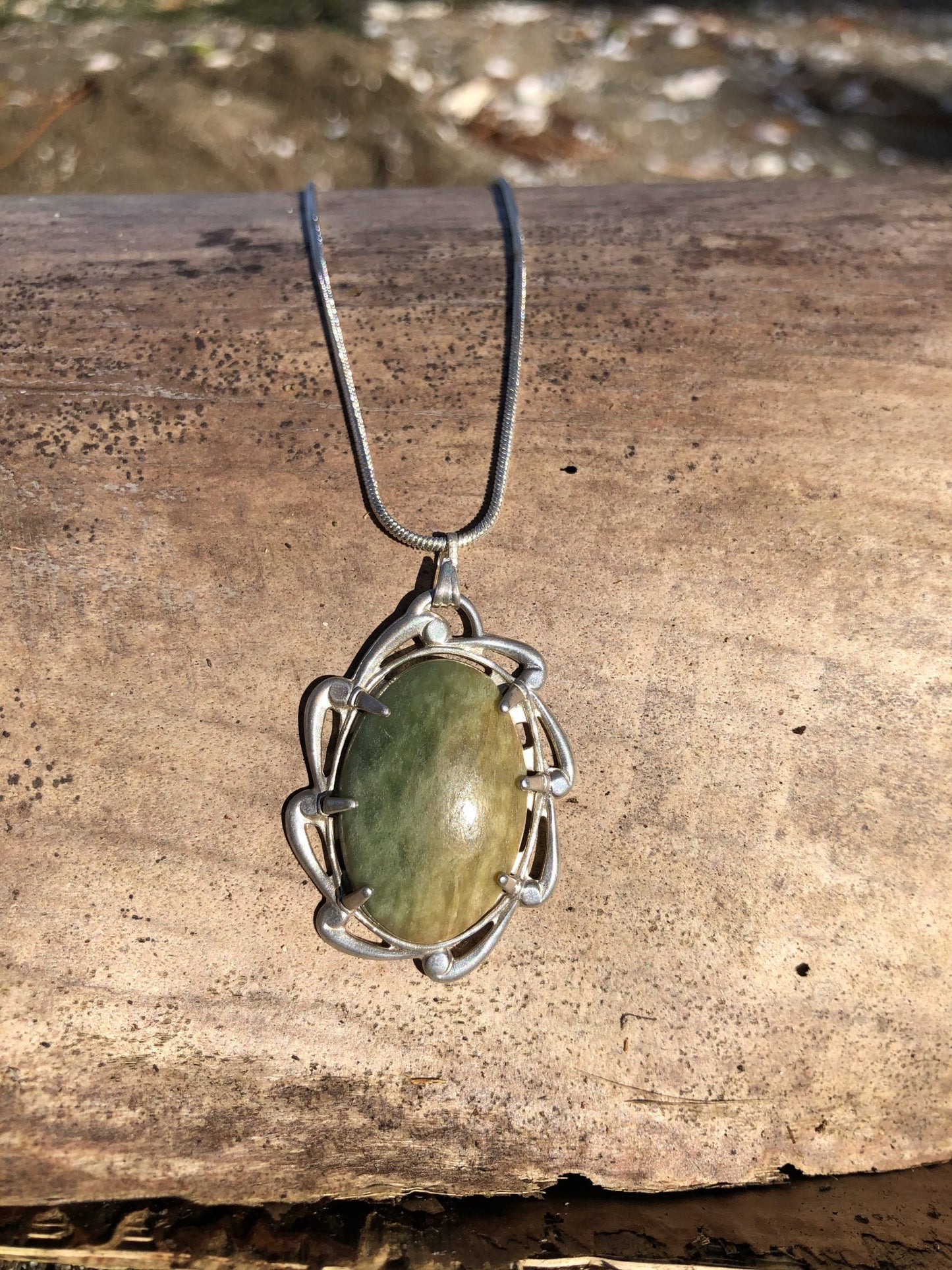 Necklace with New Zealand Marsden Flower jade (greenstone or Pounamu) with green and yellow markings, hand polished to a 25x18mm cabochon and set in sterling silver with 24 inch sterling silver snake chain on driftwood