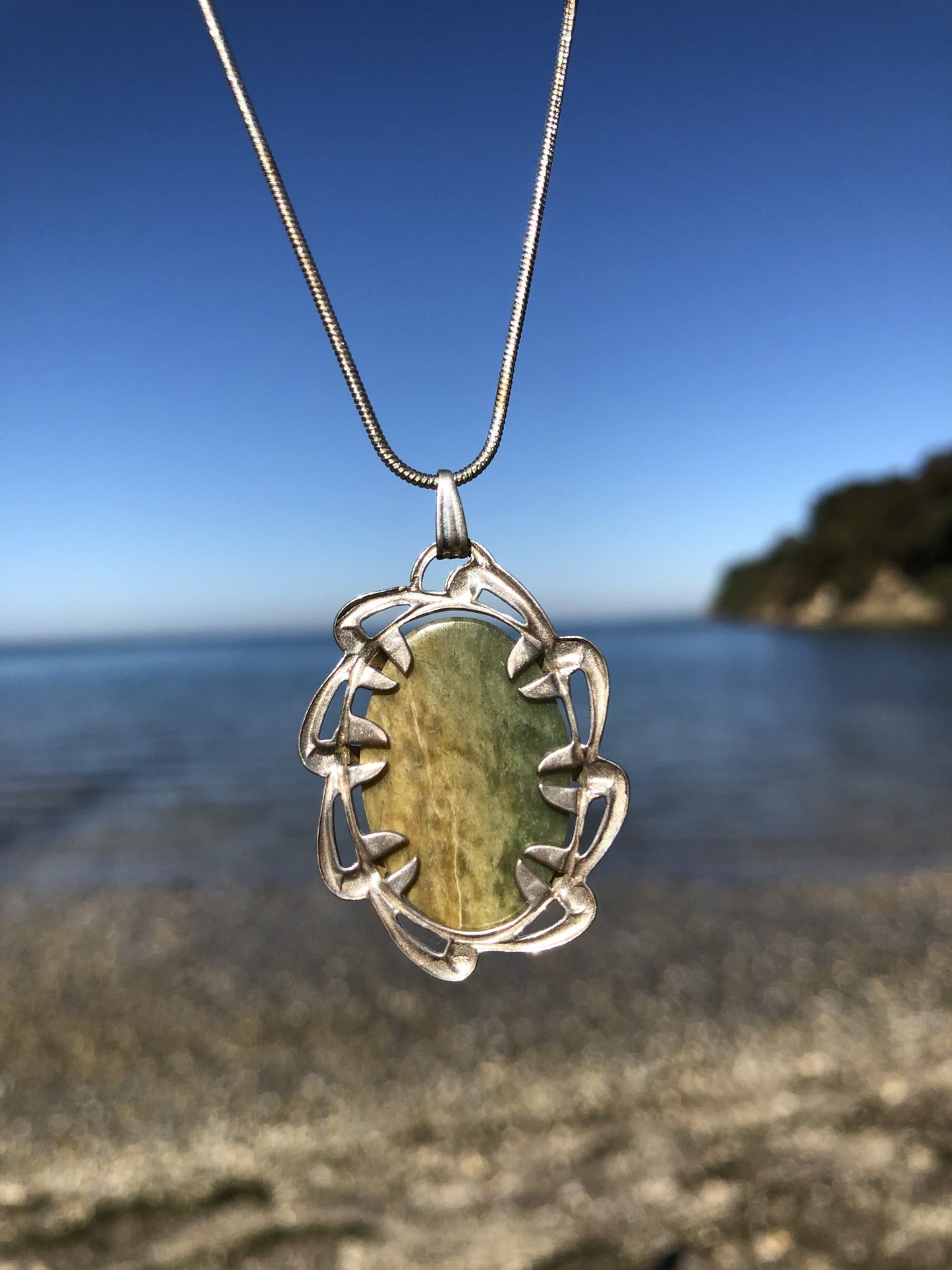 Necklace with New Zealand Marsden Flower jade (greenstone or Pounamu) with green and yellow markings, hand polished to a 25x18mm cabochon and set in sterling silver with 24 inch sterling silver snake chain, back