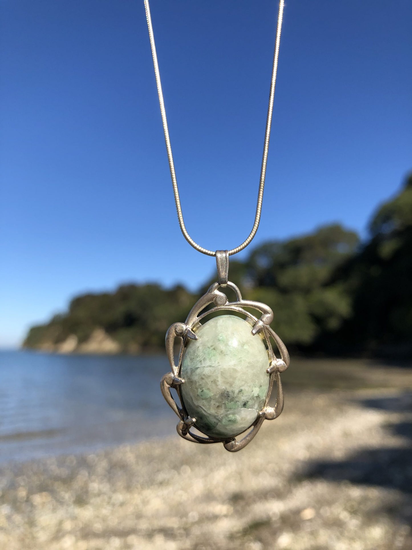 Necklace with New Zealand Hydrogrossular garnet green with white patterning from the Polaris River in Nelson and hand polished to a 25x18mm cabochon and set in sterling silver with a 24 inch sterling silver snake chain, on beach
