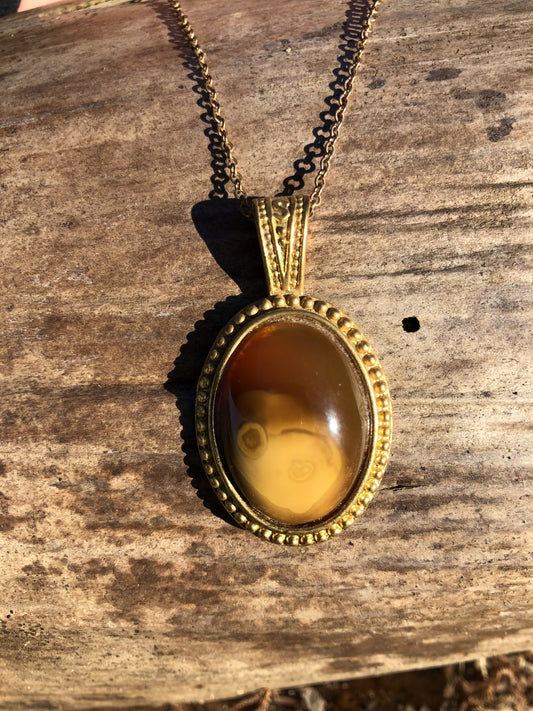 Necklace with natural New Zealand Carnelian, with sparkling translucent orange and swirling brown highlights, hand polished to a 25x18mm oval cabochon and set in a gold plated setting with 19 inch chain, front