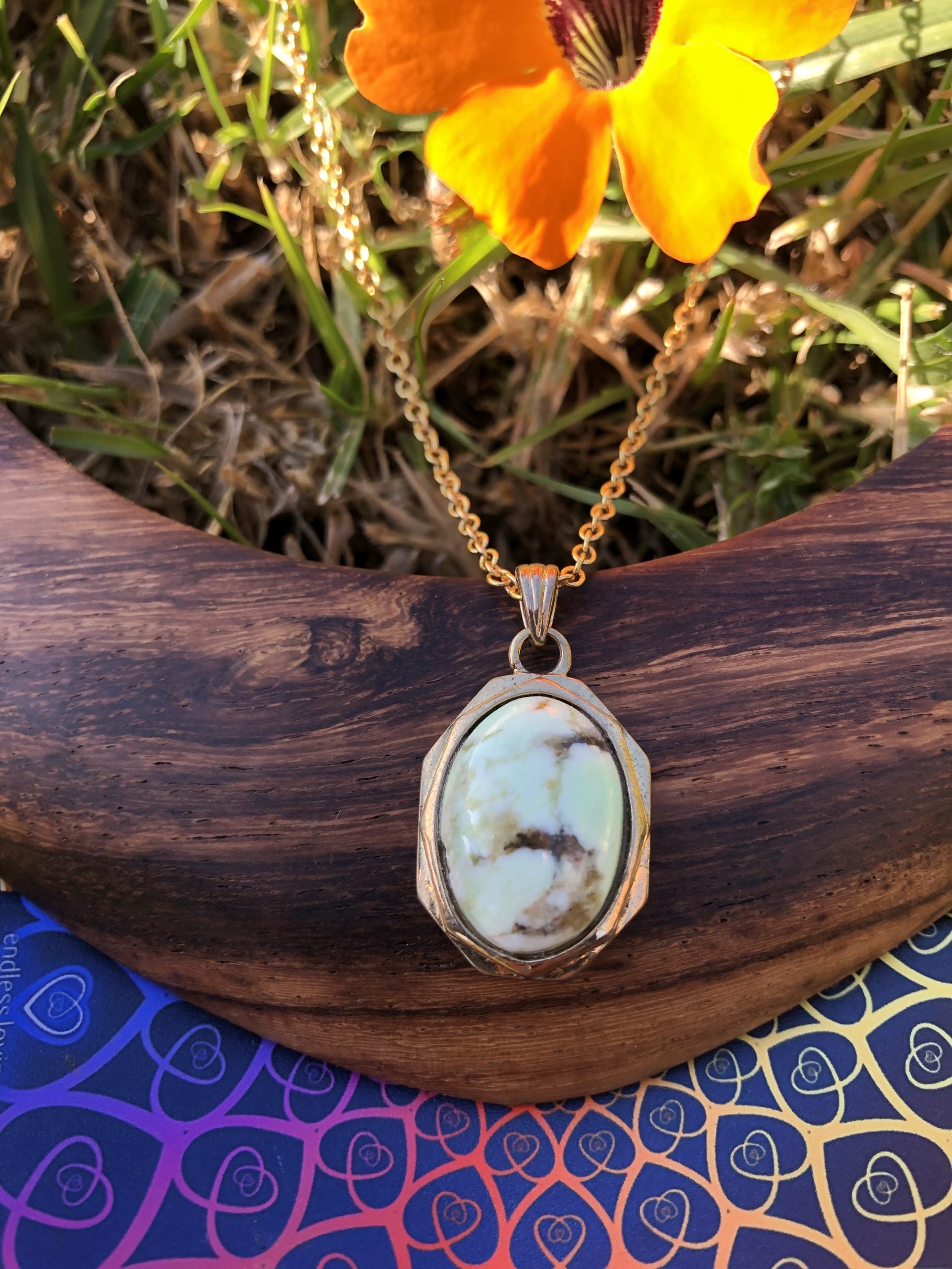 Necklace with natural lemon chrysoprase showing gentle lime green interspressed with brown-orange carnelian, hand polished to a 18x13mm cabochon and set in gold plated setting with 19 inch chain, closer