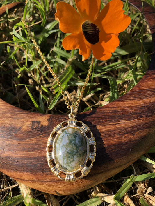 Necklace with natural Moss Agate from India, showing finely grained dark green "moss" in a transluscent milky white background, hand polished to a 20x15mm cabochon and set in gold plated setting with 19 inch chain.