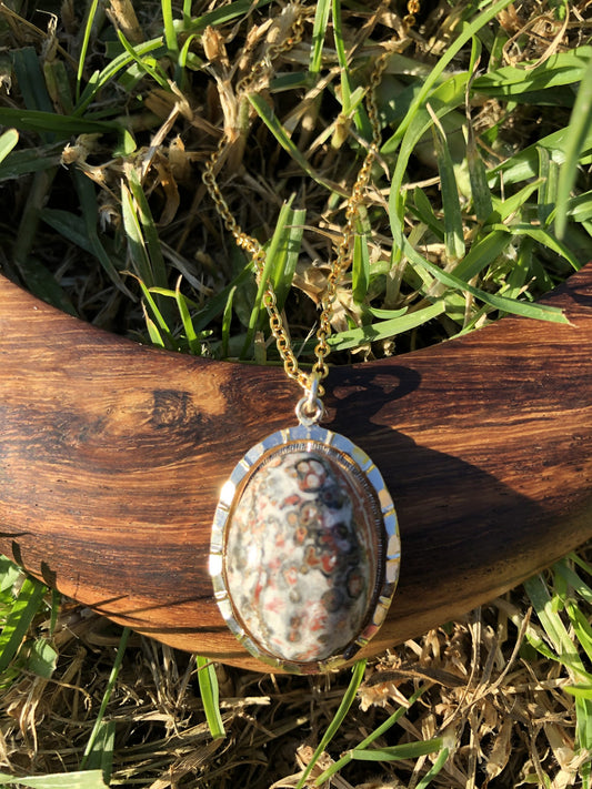 Necklace with Leopard Skin Jasper collected from Brazil, and hand polished into a 25x18mm cabochon, set in a gold-plated setting with 19 inch chain. This stone shows the characteristic pattern of this stone of pink and grey dots, lighter