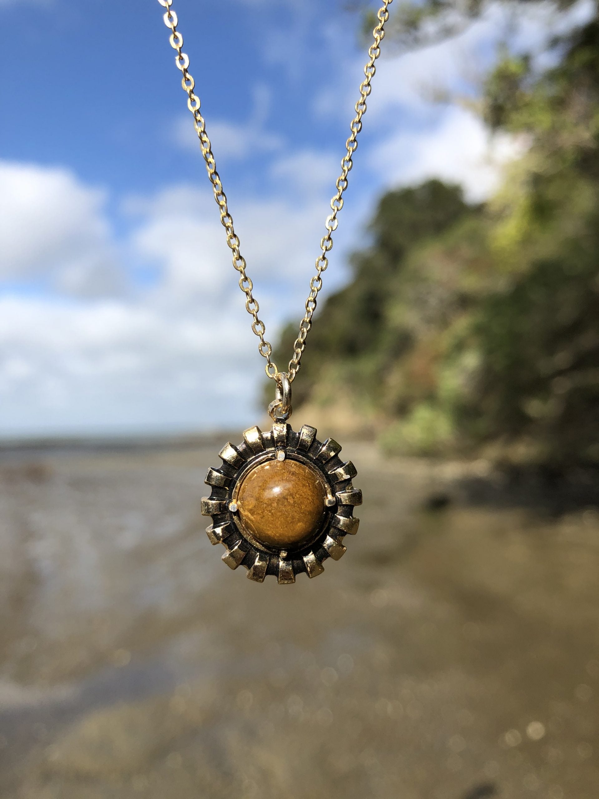Necklace with natural Fossil Chert from Coromandel New Zealand, with tiny micro-fossils in a brown background, cut to a 10mm round cabochon and set in a gold plated setting with 19 inch chain.