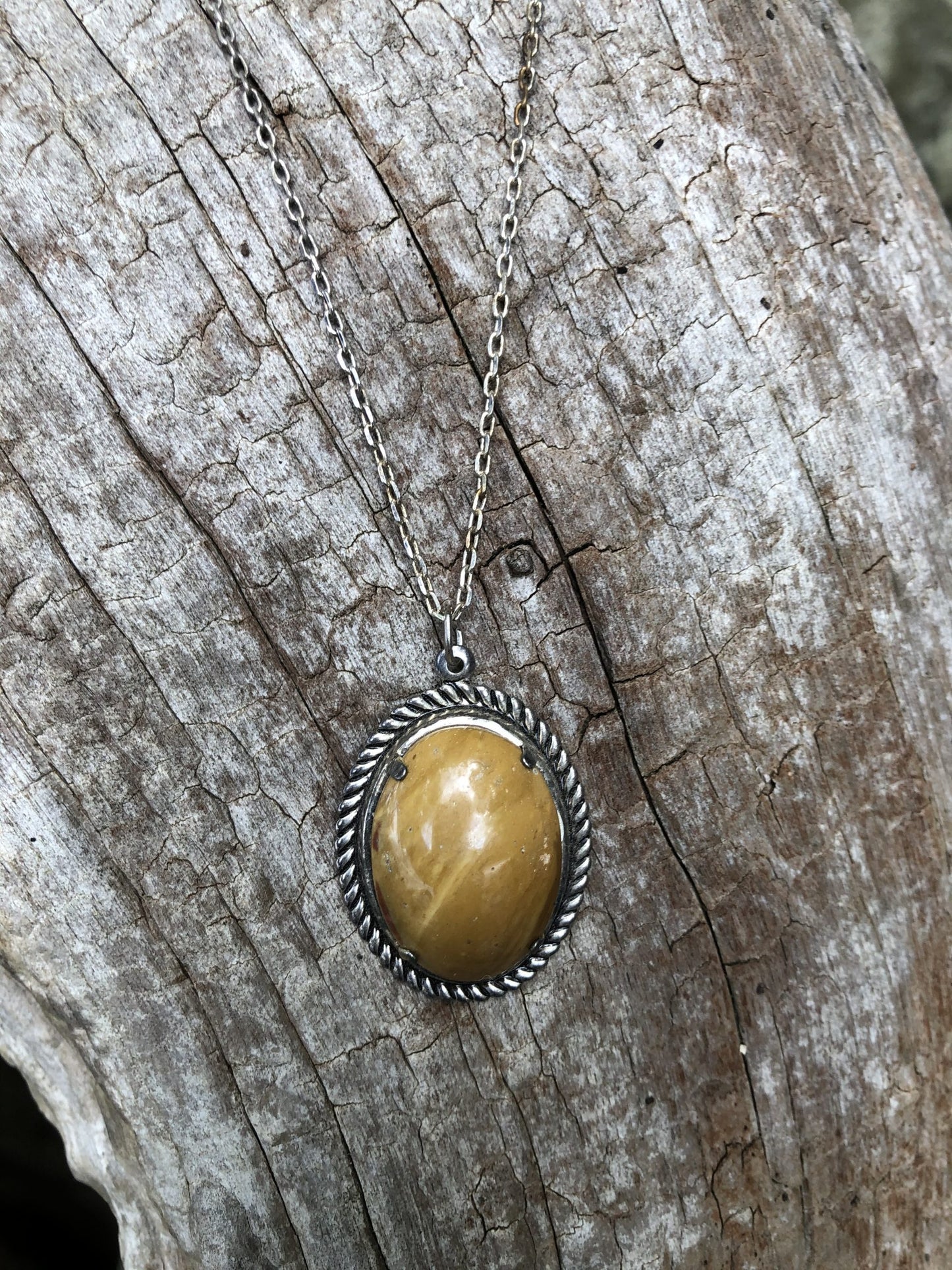 Necklace with natural petrified wood from Coromandel, New Zealand with subtle brown and tan tones along the grain lines, hand polished to a 25x18mm cabochon and set in a silver-plated setting with 19 inch chain on log