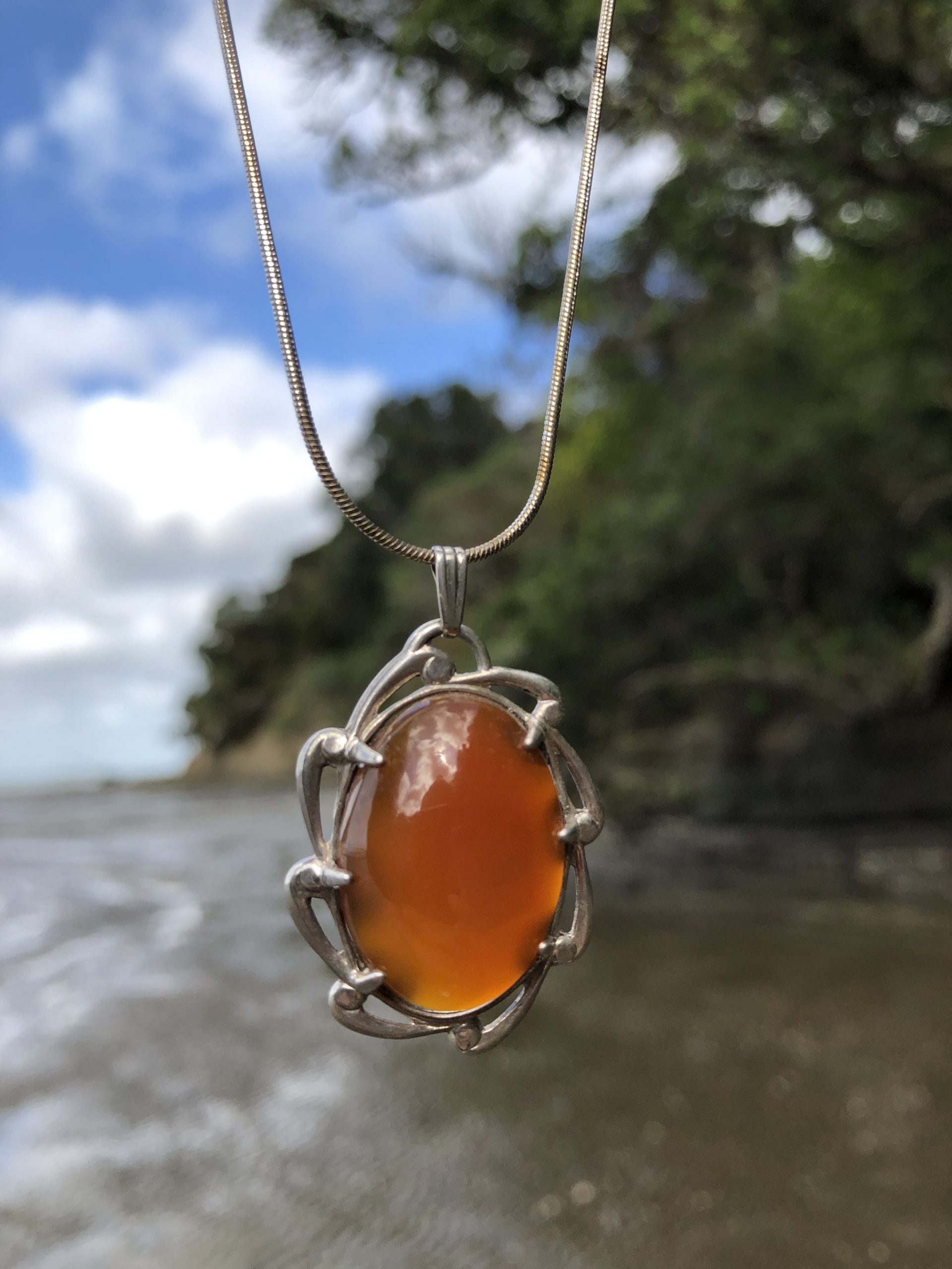 Necklace with a flawless caramel orange New Zealand Carnelian, hand polished to a 25x18mm cabochon and set in a sterling silver setting with a 20 inch sterling silver snake chain, angled