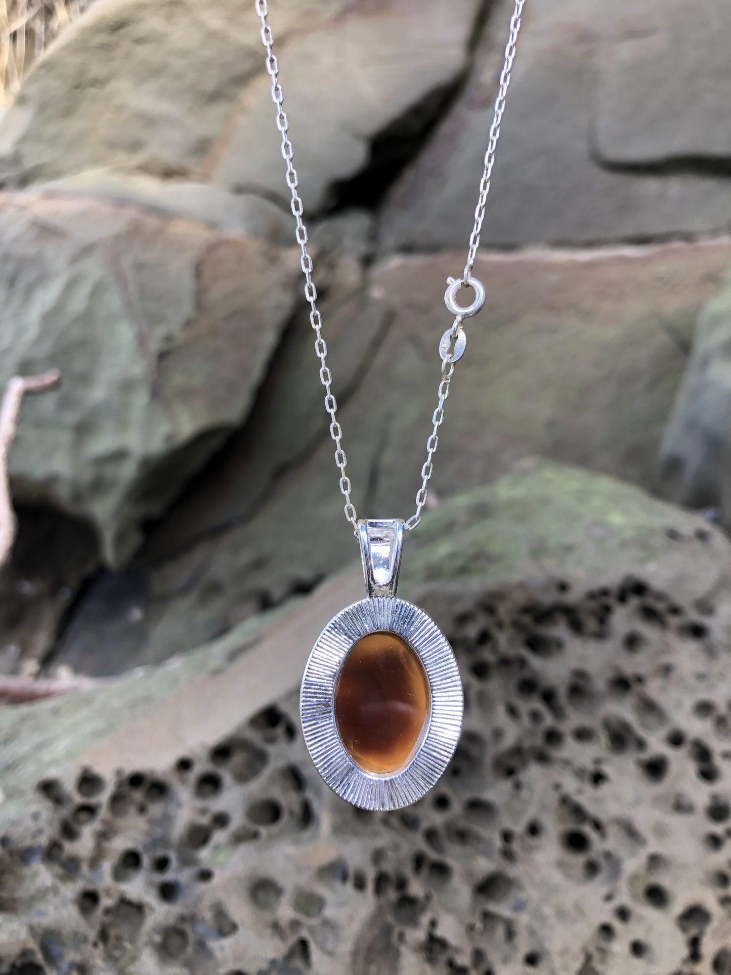 Necklace with natural New Zealand Carnelian, with sparkling translucent orange glowing through swirling browns, hand polished to a 25x18mm oval cabochon and set in a silver-plated setting with 19 inch chain, back